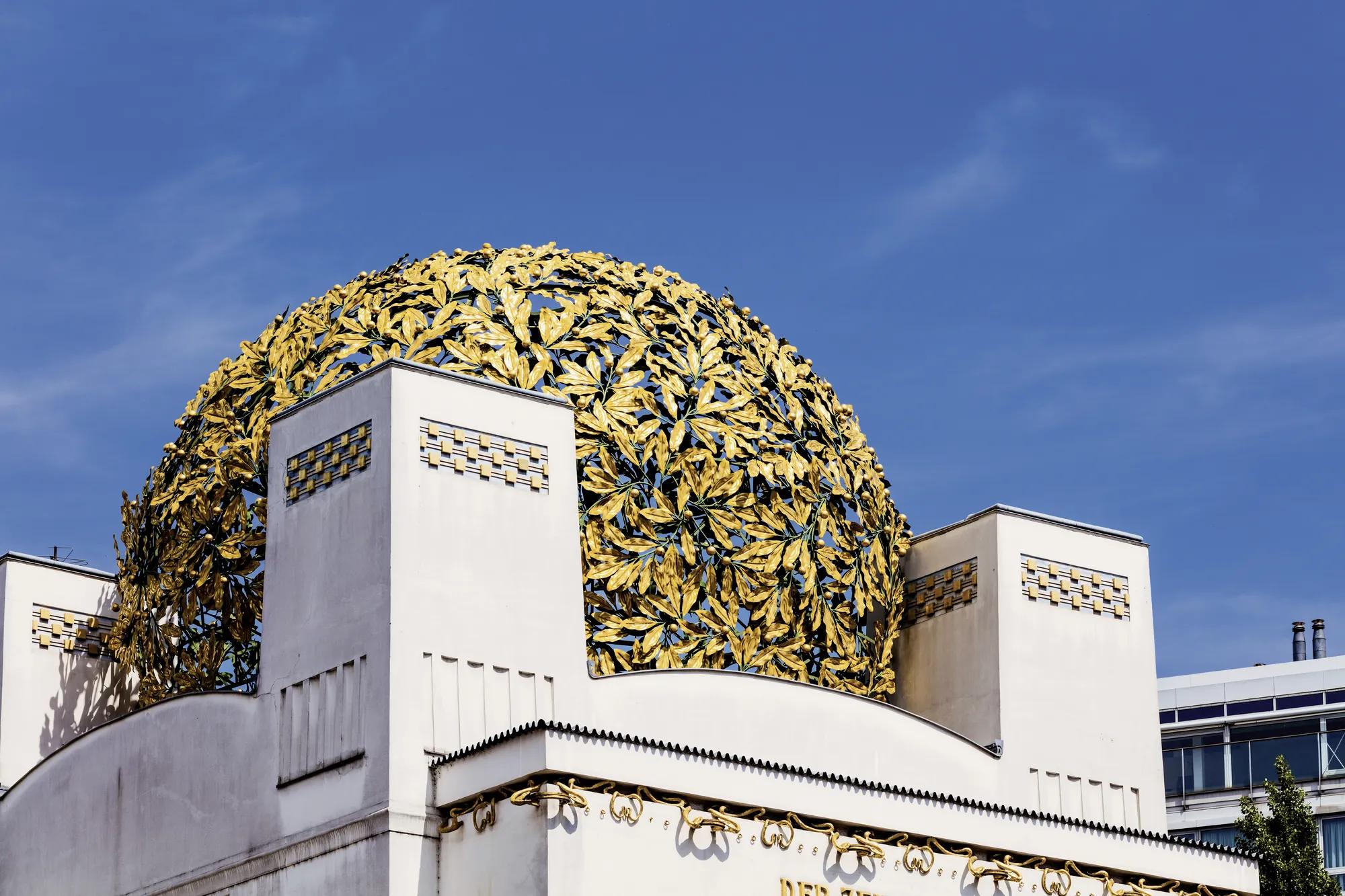 Golden dome of the Vienna Secession Building, a landmark of Jugendstil architecture, set against a clear blue sky.