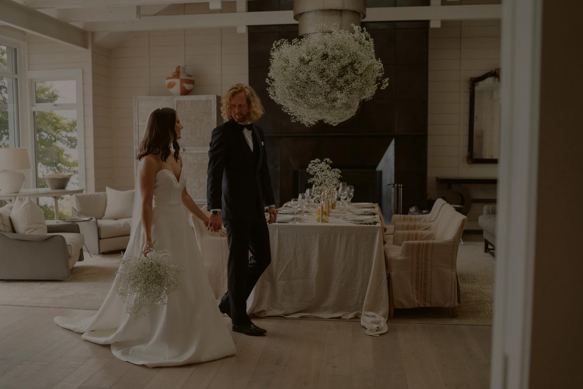 Bride and Groom hold hands walking down a private path at Rosewood Matakauri, the path is surrounded by lush green native plantings.