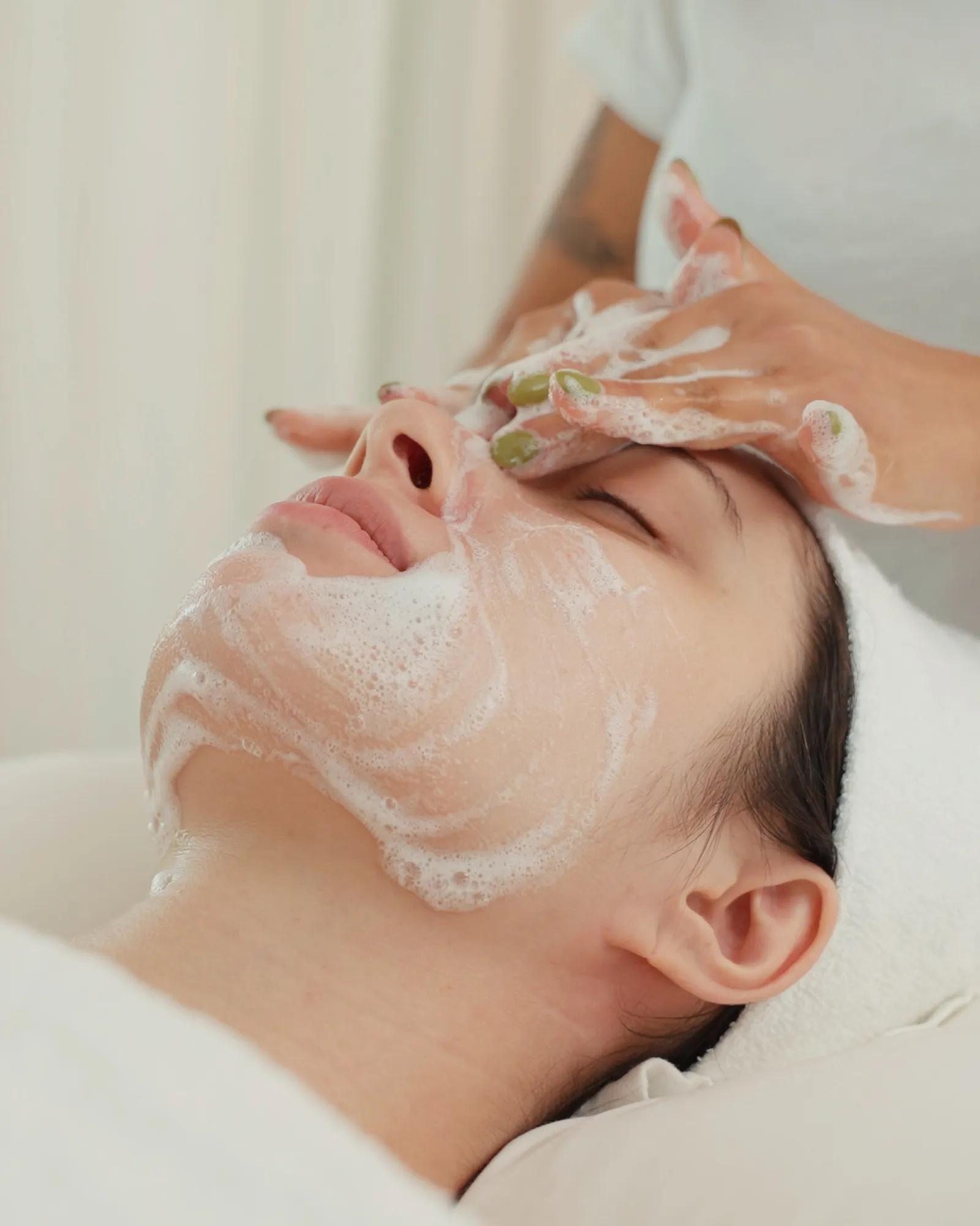 Close up shot of a woman’s face with her eyes closed and relaxed as she gets a facial at a luxury spa.