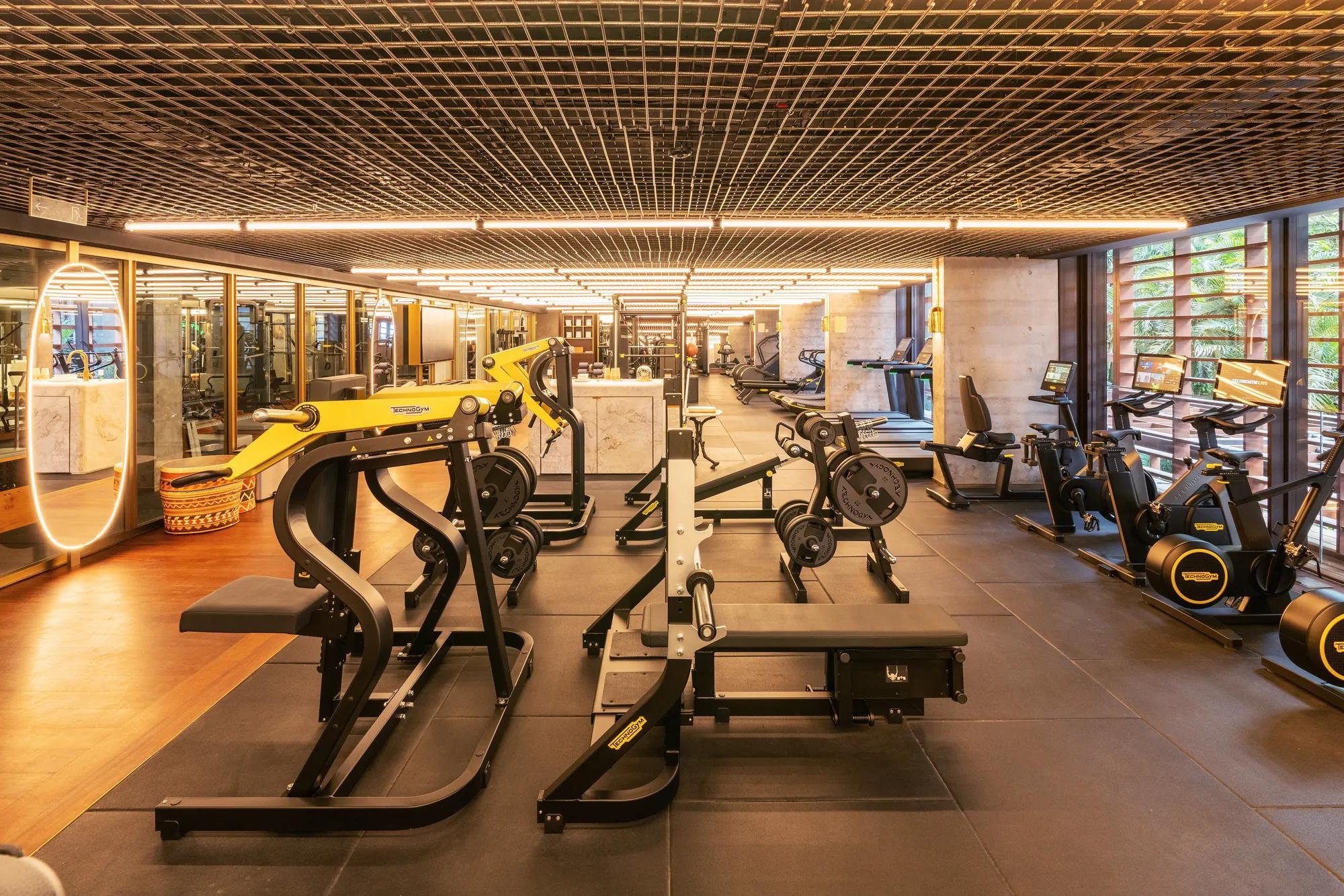 A photo of the Fitness Center at Rosewood São Paulo, featuring equipment such as a bench press, dumbbells, and treadmills.