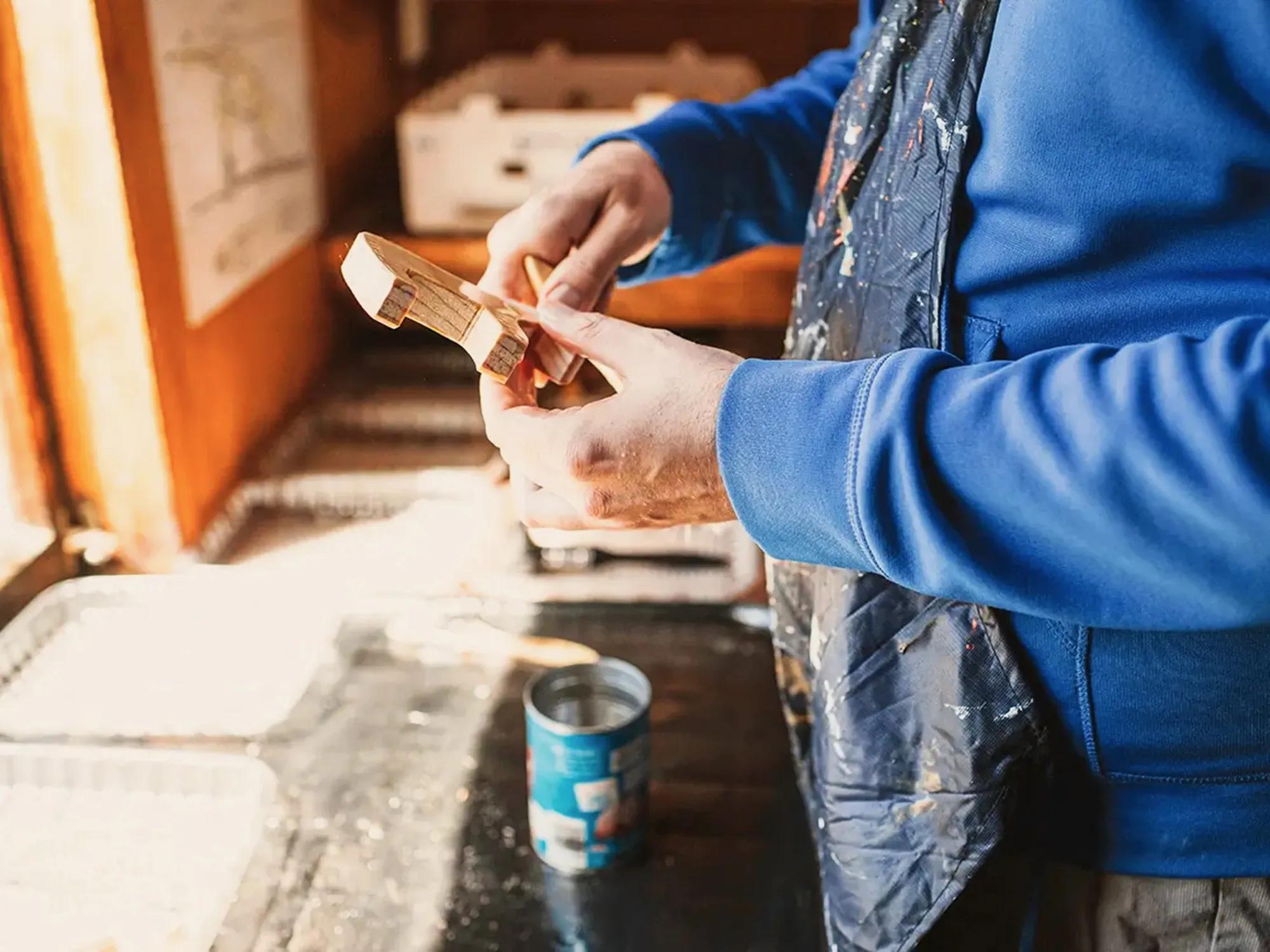Close up shot of a person in a workshop hand carving a wooden toy.   