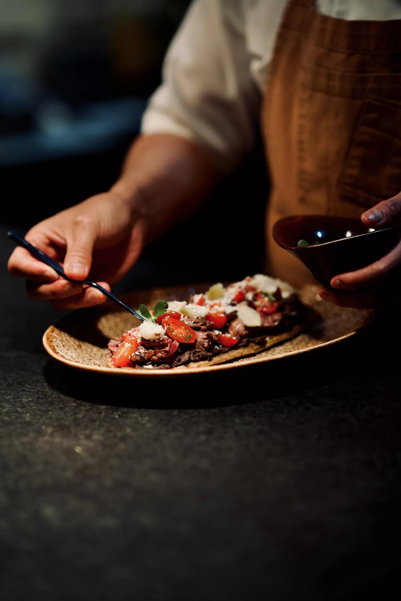 Artist’s hands painting a colorful mask on a table, surrounded by various paint supplies and brushes in a creative art studio.