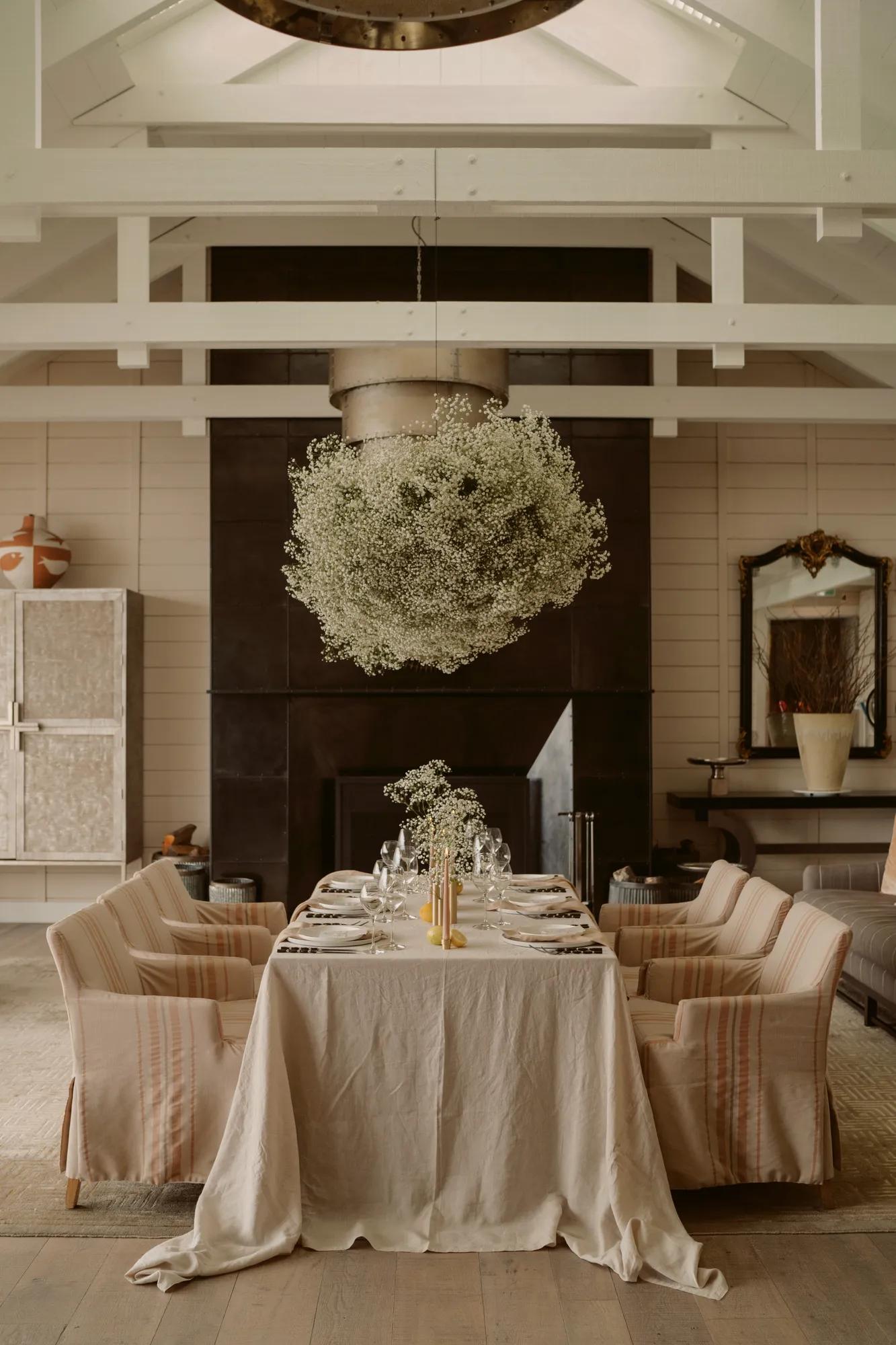 Beautifully set table for an intimate wedding in a luxury villa at Rosewood Matakauri with simple white flower installation hanging above.