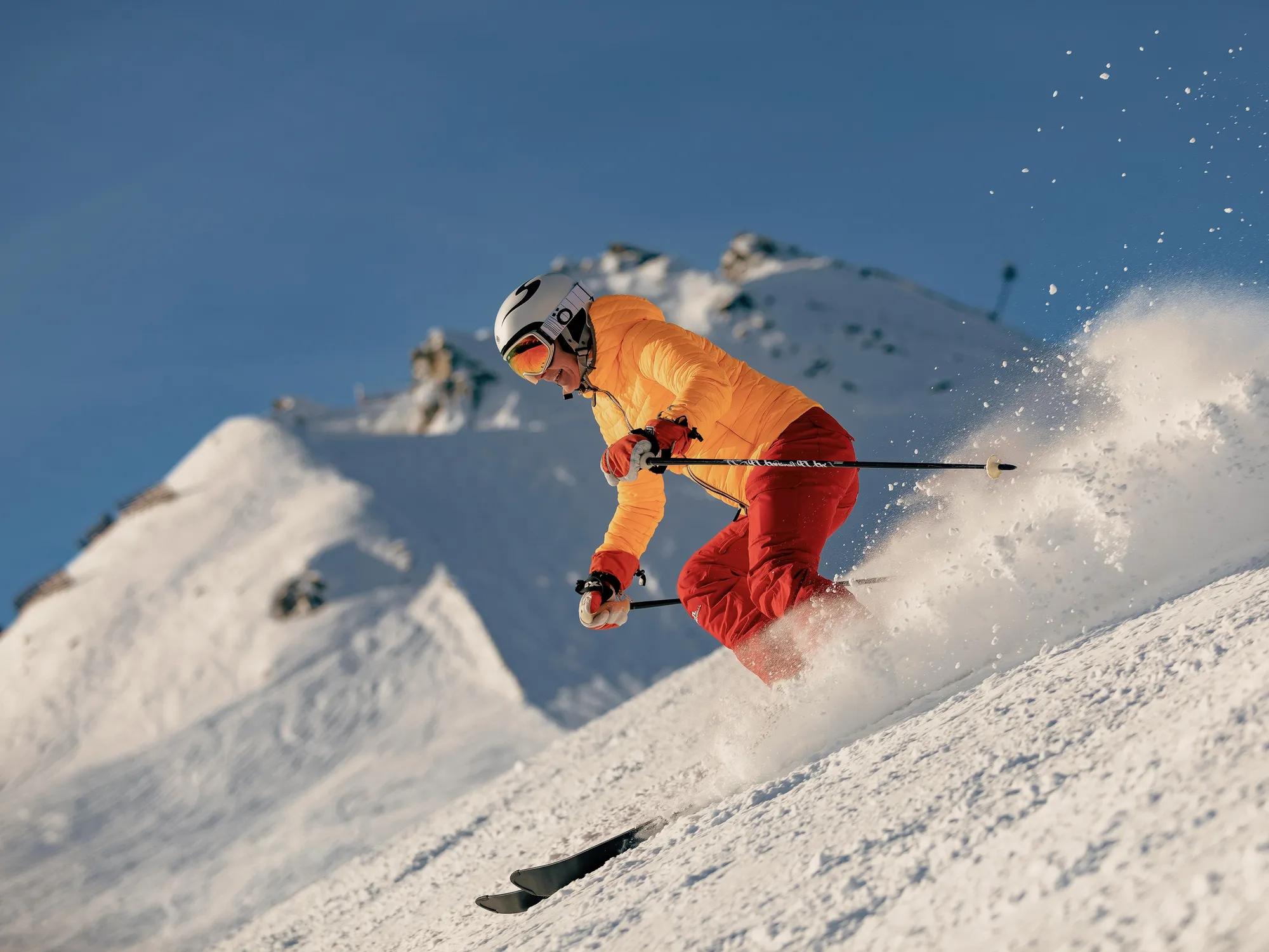 Skier skiing down untouched powder on a early morning run with the Southern Alps in the background.