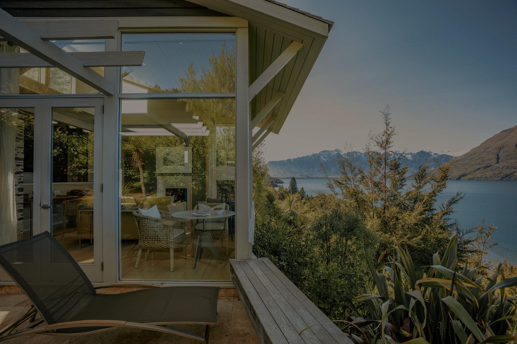Private balcony off a luxury hotel room with sun lounger looking out to lake and mountain views. 