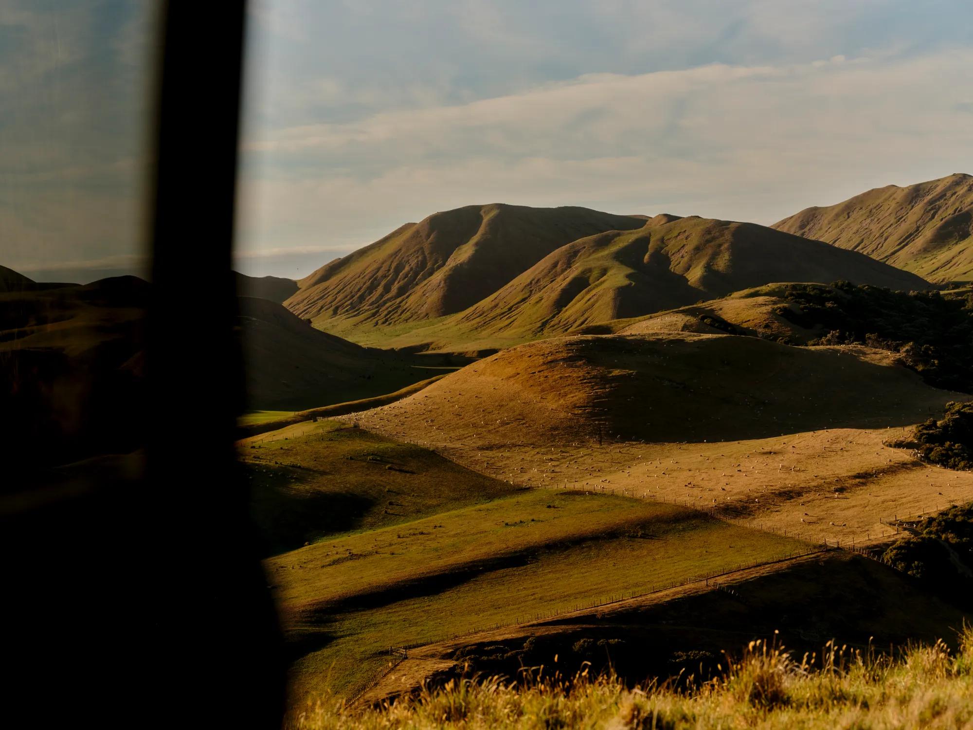 Rolling hills and distant mountains framed by a window in warm sunlight.