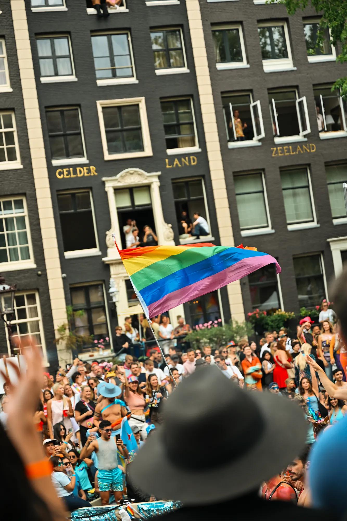 Pride flag and people celebrating with canal houses in the back