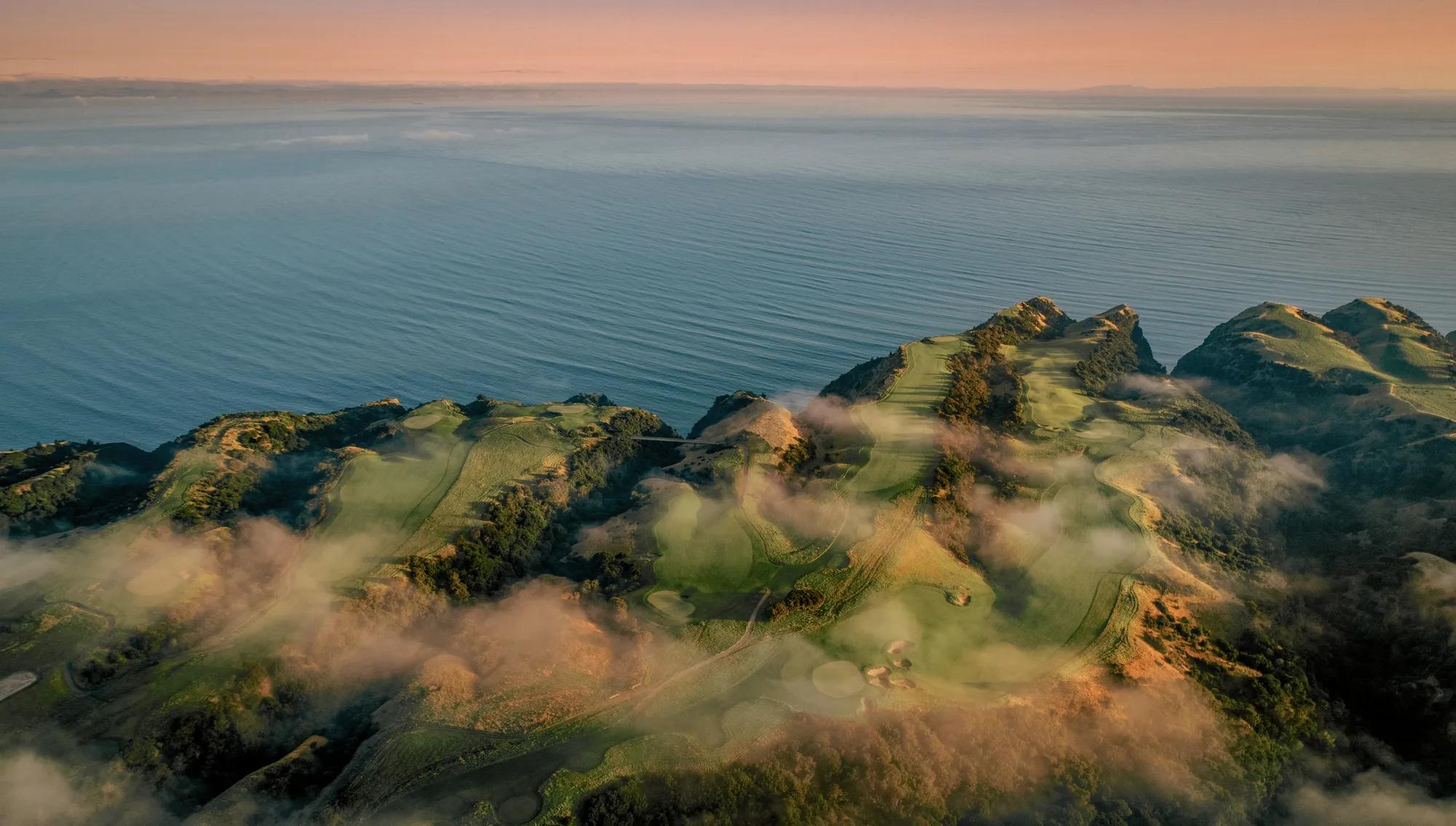 Bird's eye view of the striking ridge and valley landscape of the Cape Kidnappers peninsula, with the ocean stretching out to the horizon. 