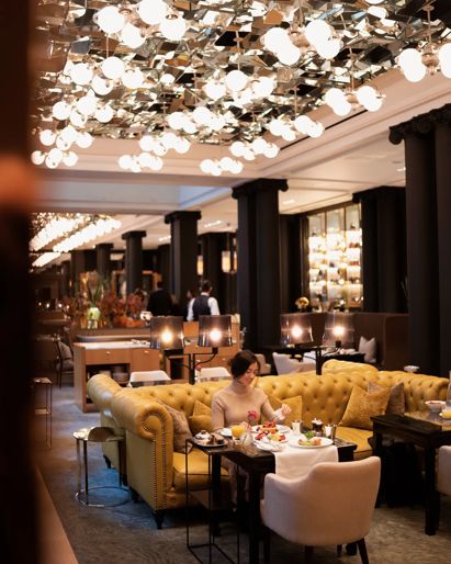 Elegant Mirror Room dining interior with plush seating, chandeliers and tables set for breakfast.