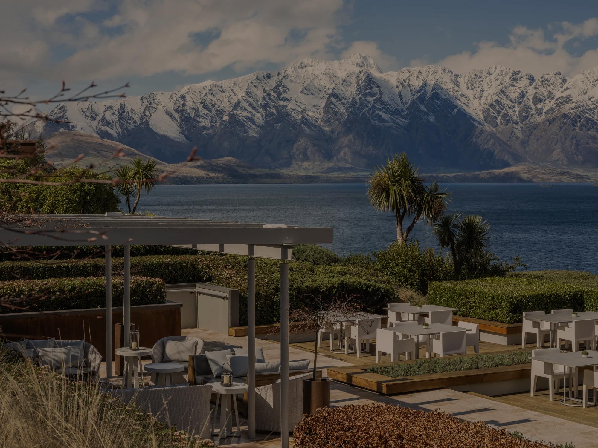 Overlooking the Remarkables Terrace at Rosewood Matakauri with various dining space, pergola, and panoramic lake and mountain views.