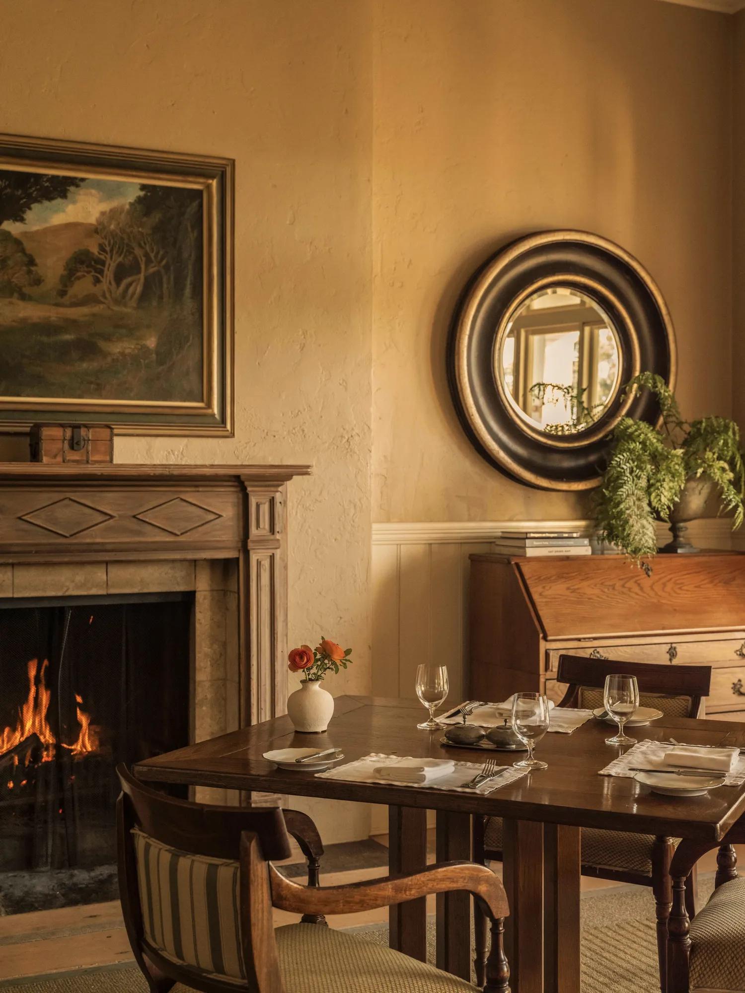 Classically styled dining room, with timber dining table and an ornate open fireplace.