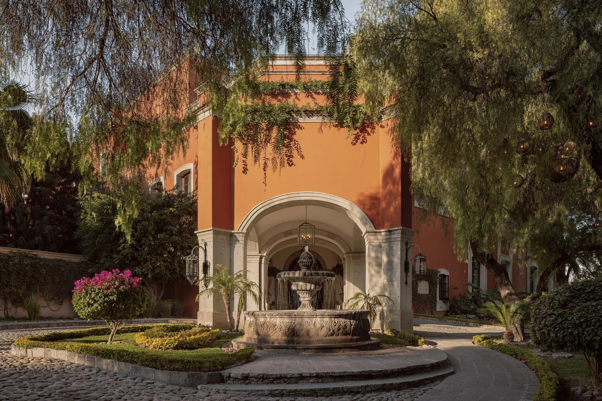 Fountain at the hotel entrance, surrounded by trees decorated with glowing wooden spheres.