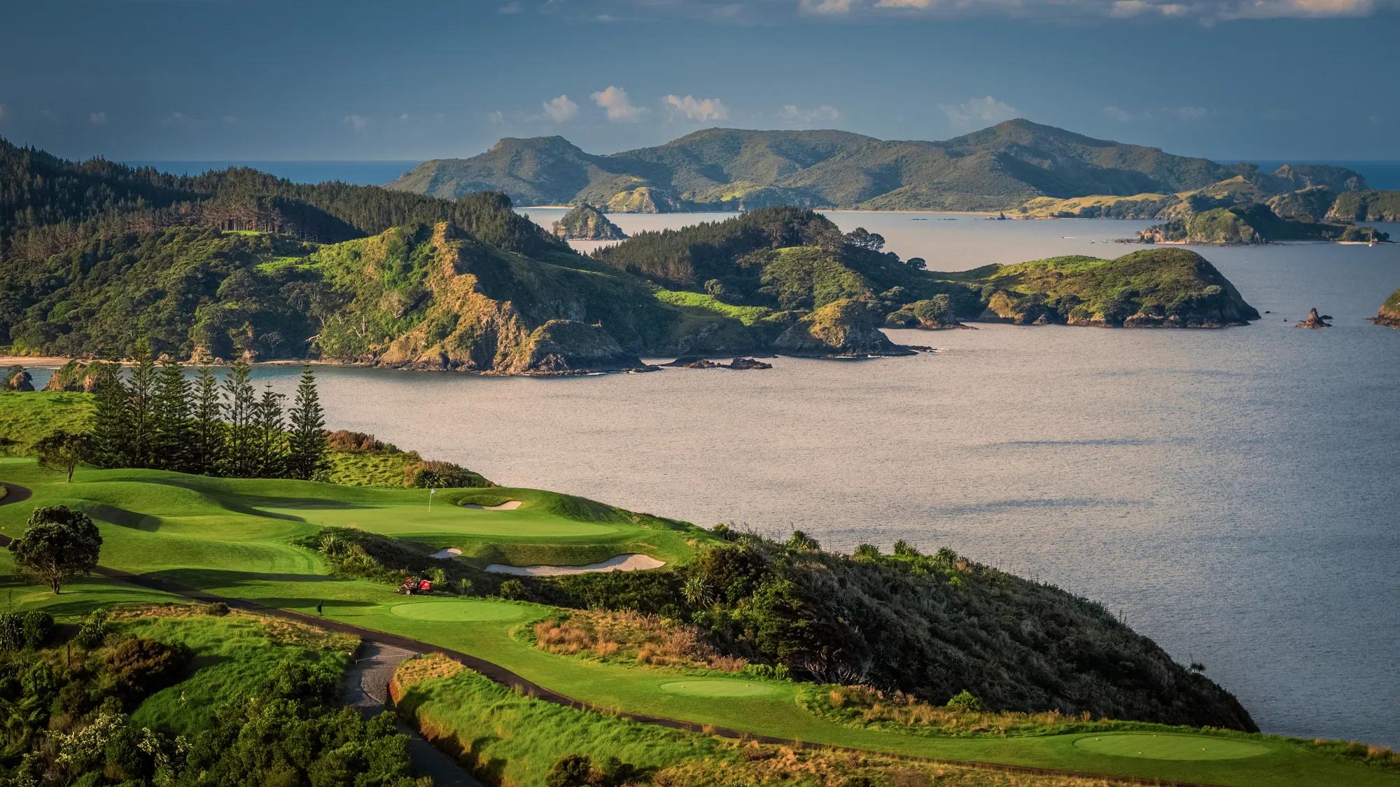 Aerial view over a verdant golf course looking out to the Cavalli Islands and ocean in the background. 