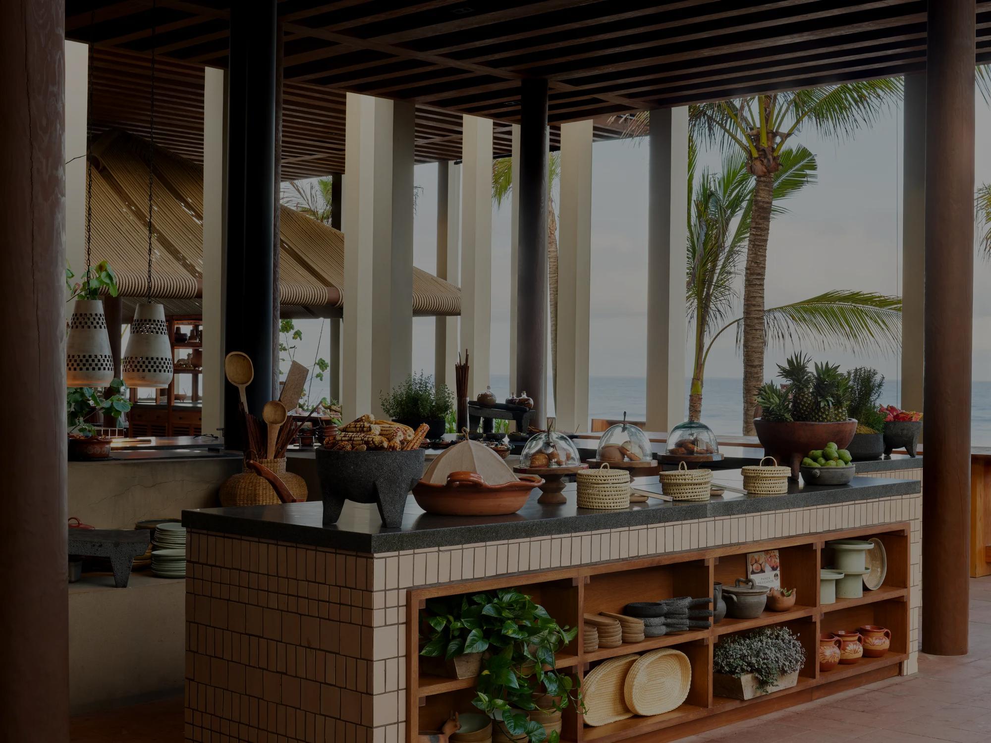 Open-air kitchen with a tiled island, tropical decor, and a view of palm trees and the ocean