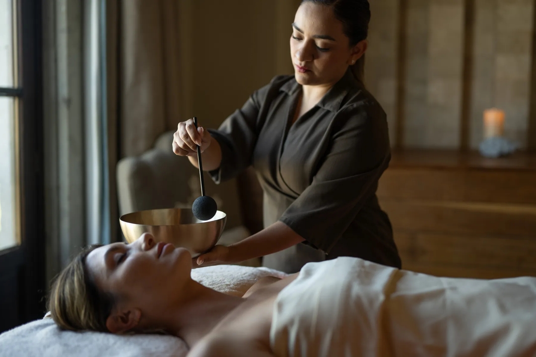 Tranquil spa relaxation room featuring a mix of individual and double seating, reclining loungers with privacy curtains, and wooden tables with magazines and decorative accents.