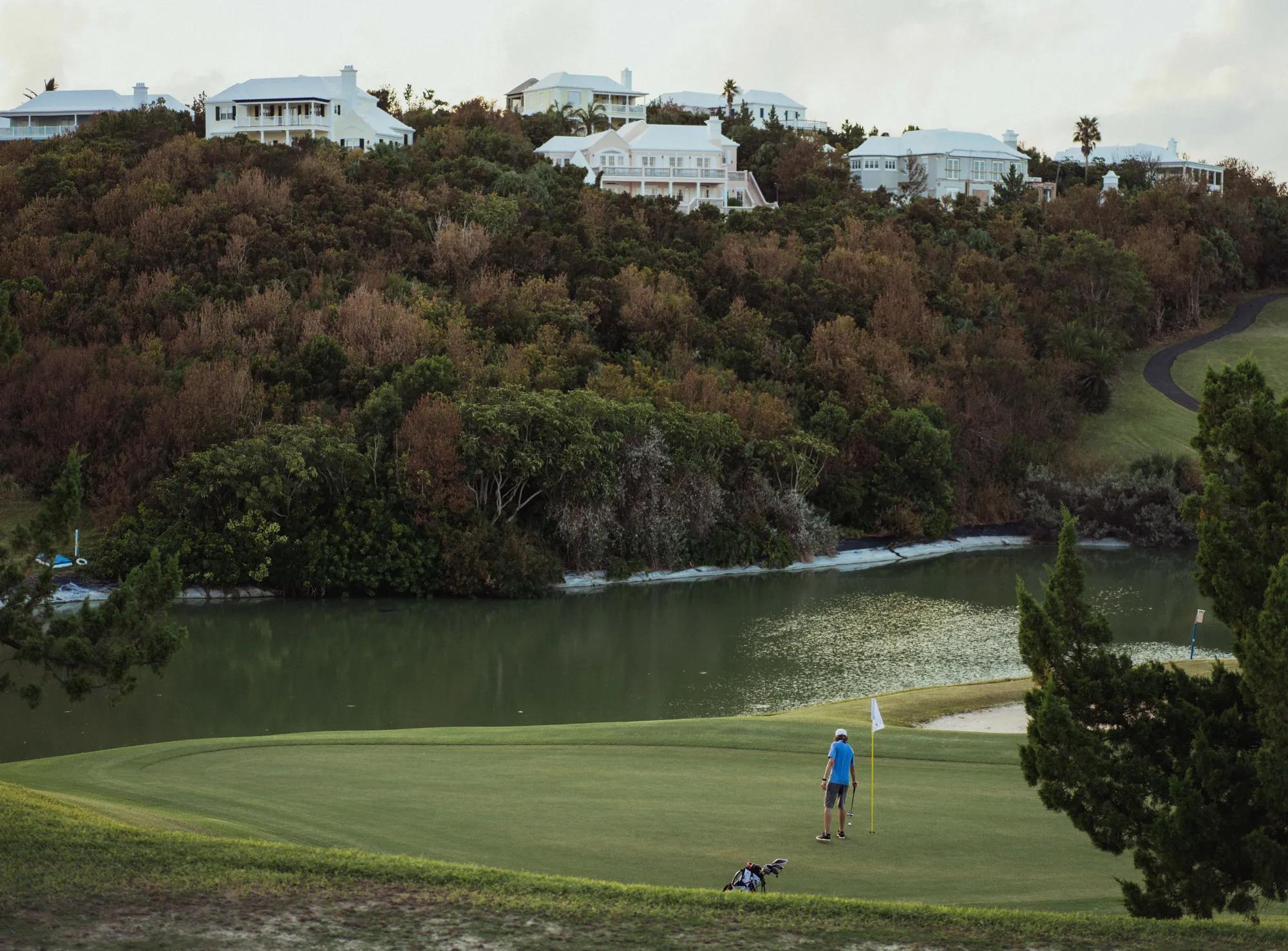 Morning golfer on the green overlooking Rosewood Bermuda and water