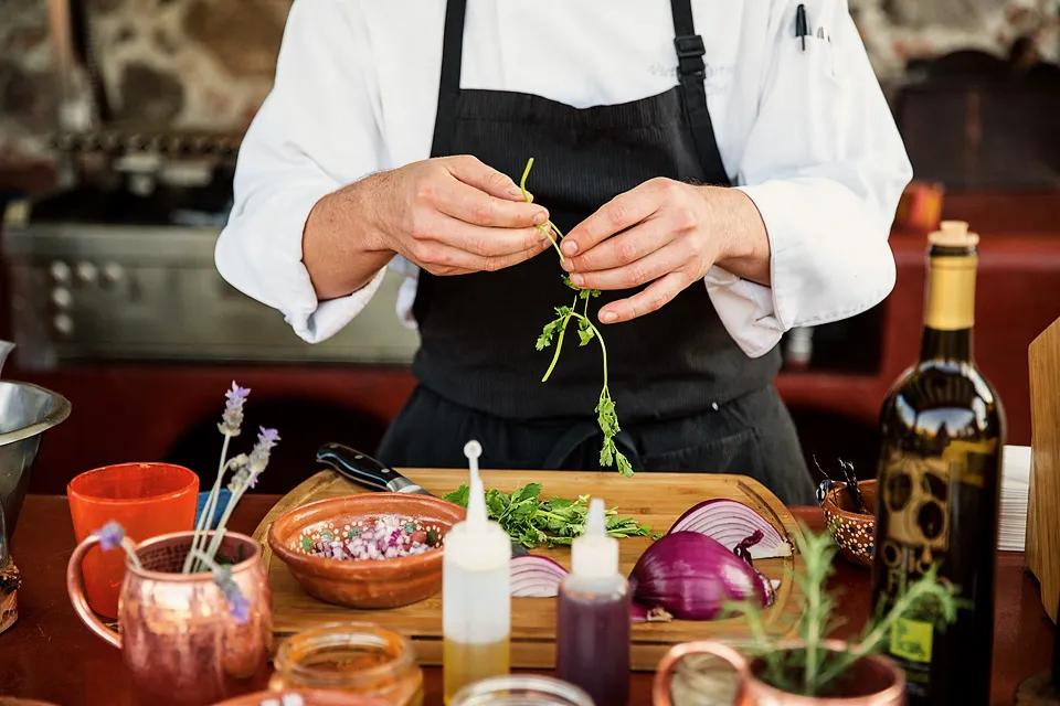 Chef preparing a dish during a hands-on cooking class, with ingredients and utensils laid out on the counter.