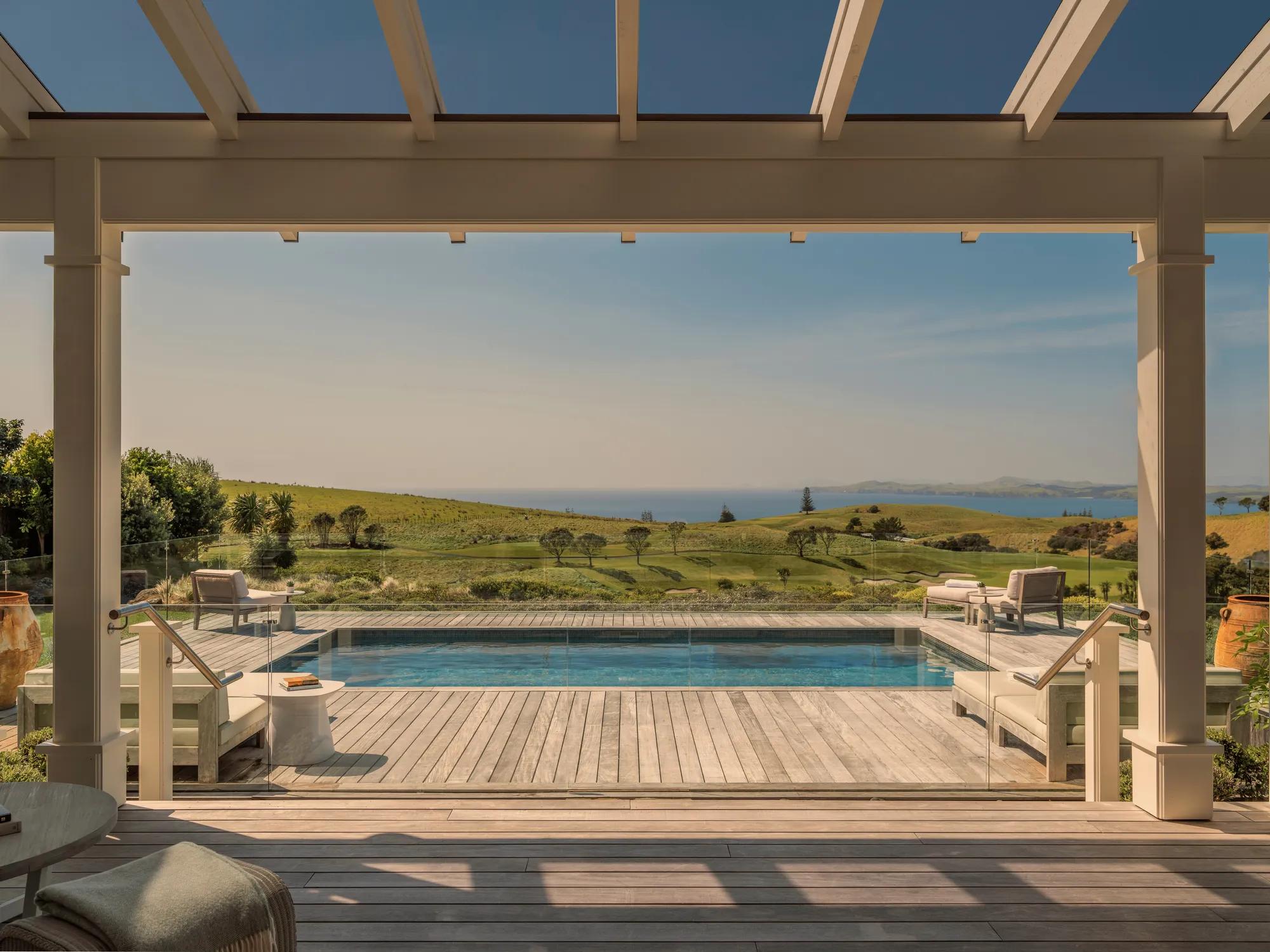 Covered deck leading out to a pool in a luxurious contemporary villa at Rosewood Kauri Cliffs, panoramic views of the ocean beyond.