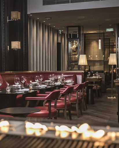 Hotel restaurant in Phnom  Penh with burgundy leather  banquettes and dark wood  paneling.