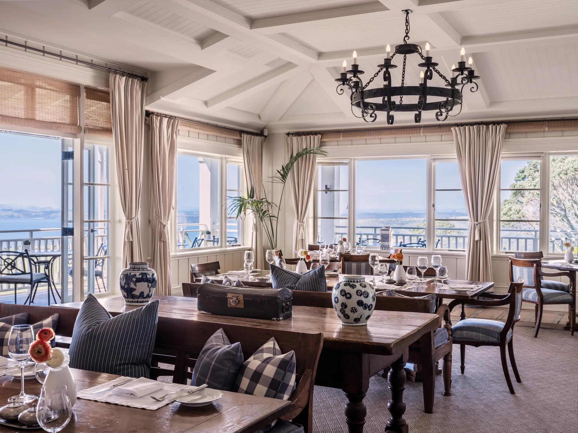 Main dining room at Rosewood Kauri Cliffs with elegant interiors, grand chandelier and views out to the Pacific Ocean.