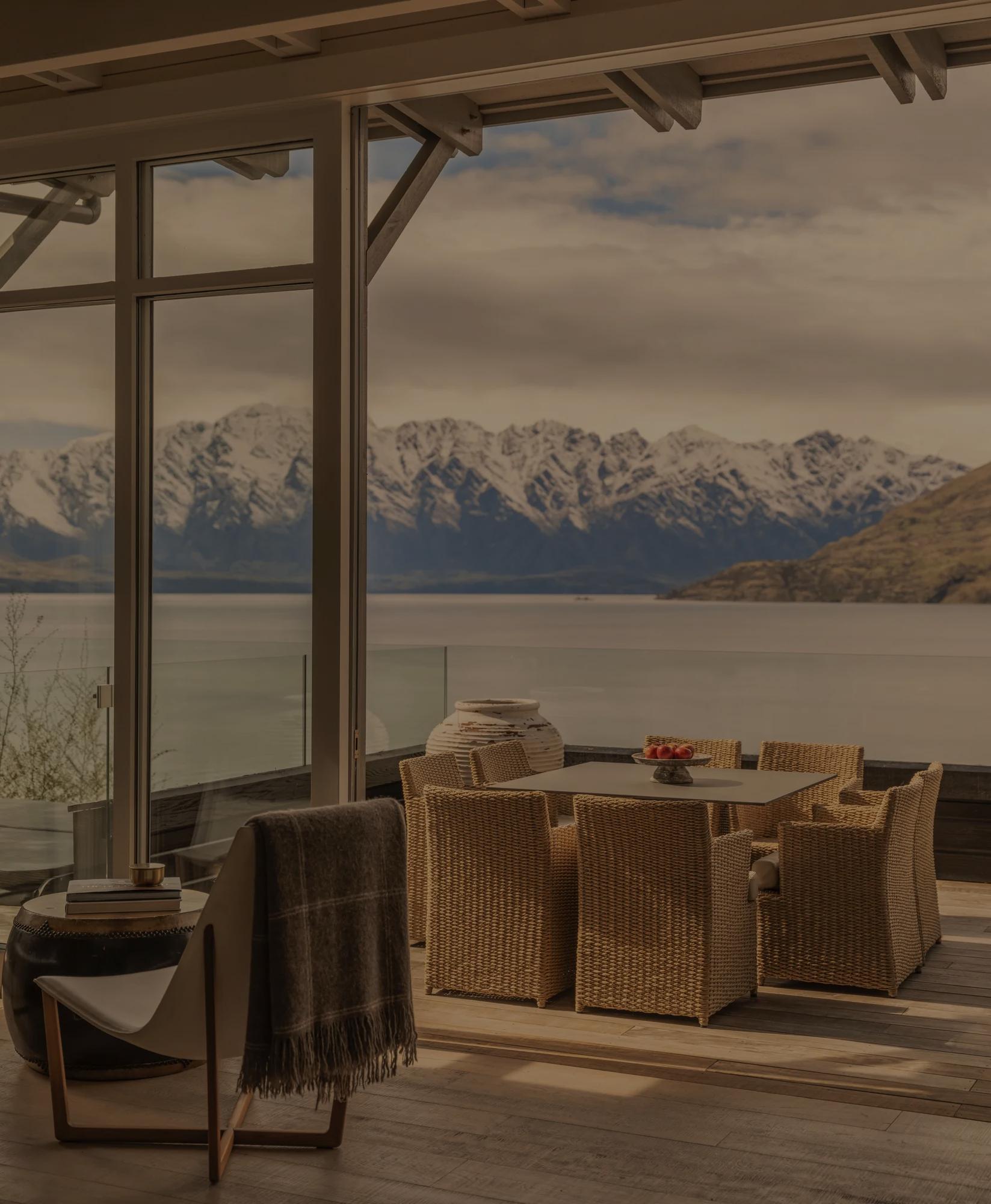 Spacious balcony off the living area of a luxurious villa with large outdoor dining table and expansive lake and mountain views.