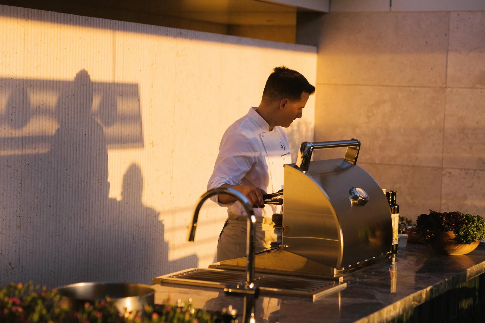 Chef grilling at a barbecue, bathed in warm sunset light