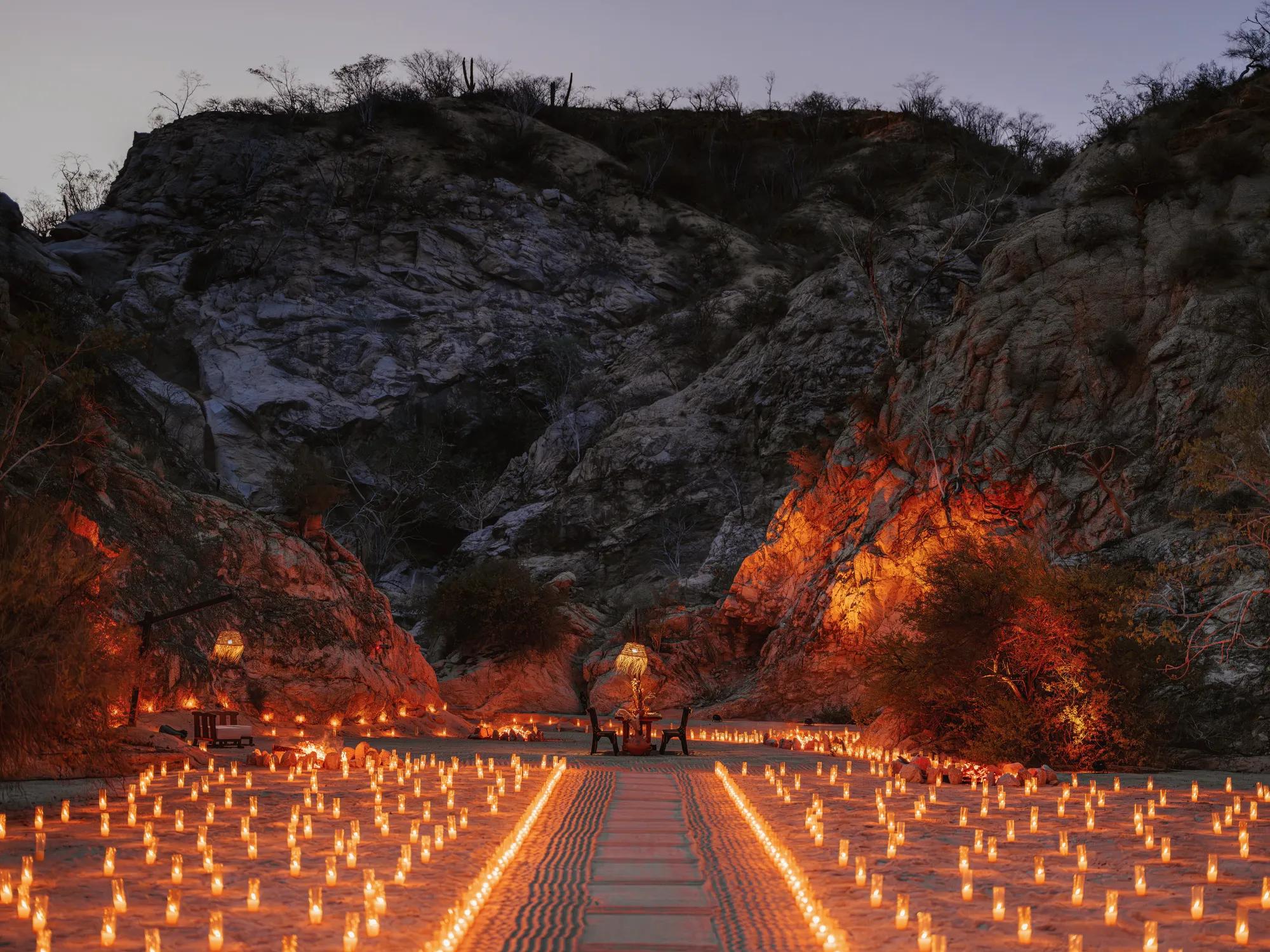 Elegant desert canyon dinner setup at Las Ventanas al Paraíso, featuring candlelit tables, scenic desert views, and a warm, inviting atmosphere