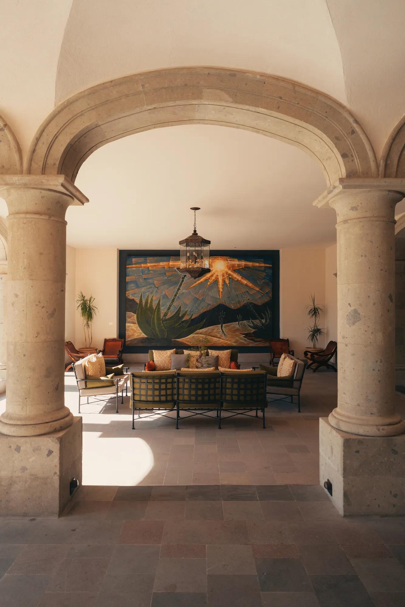 Long wooden table set for 14 guests inside a wine cellar, surrounded by wine shelves and soft lighting, with a framed artwork on the wall.