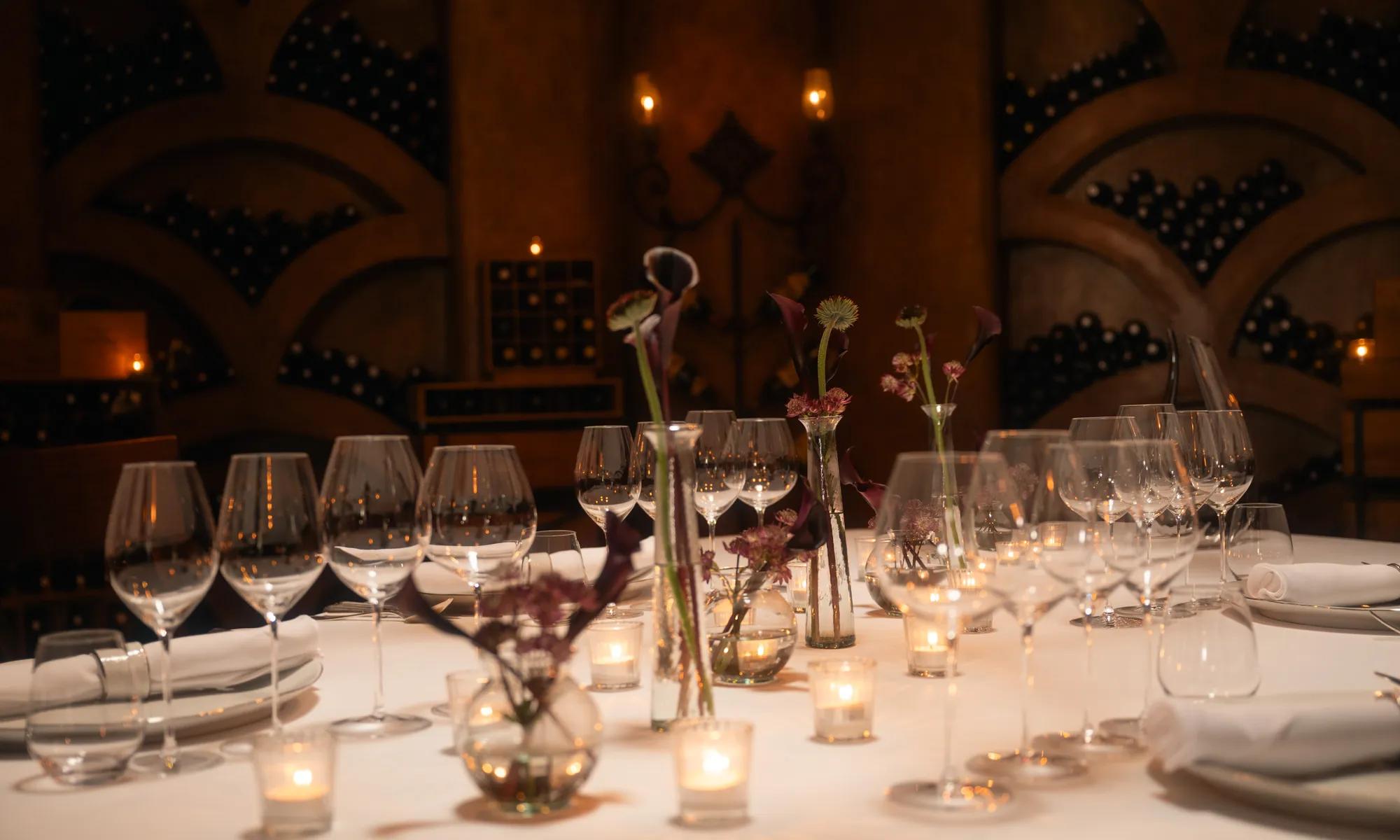 Private dining setup inside a wine cellar, surrounded by shelves of fine wines, creating an intimate and elegant atmosphere