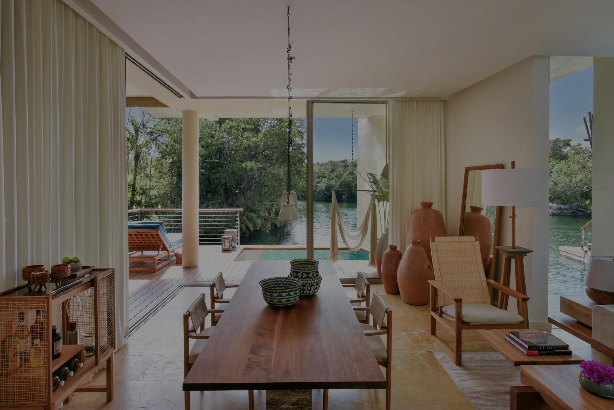 Living area of the Overwater Lagoon Suite featuring elegant, minimalistic furniture, with a terrace in the background overlooking the emerald lagoon.