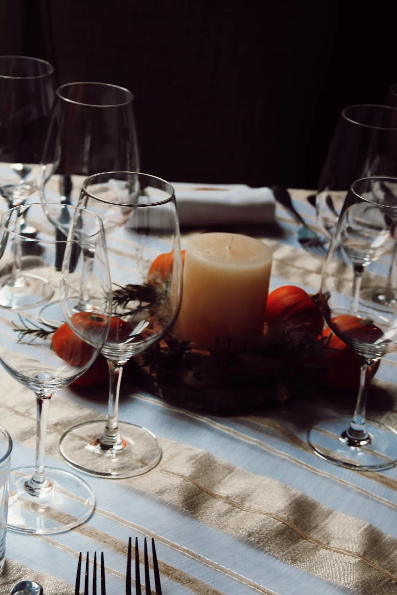 Table centerpiece with small pumpkins and a candle, set on a table with a tablecloth, glassware, and a complete place setting in San Miguel de Allende.