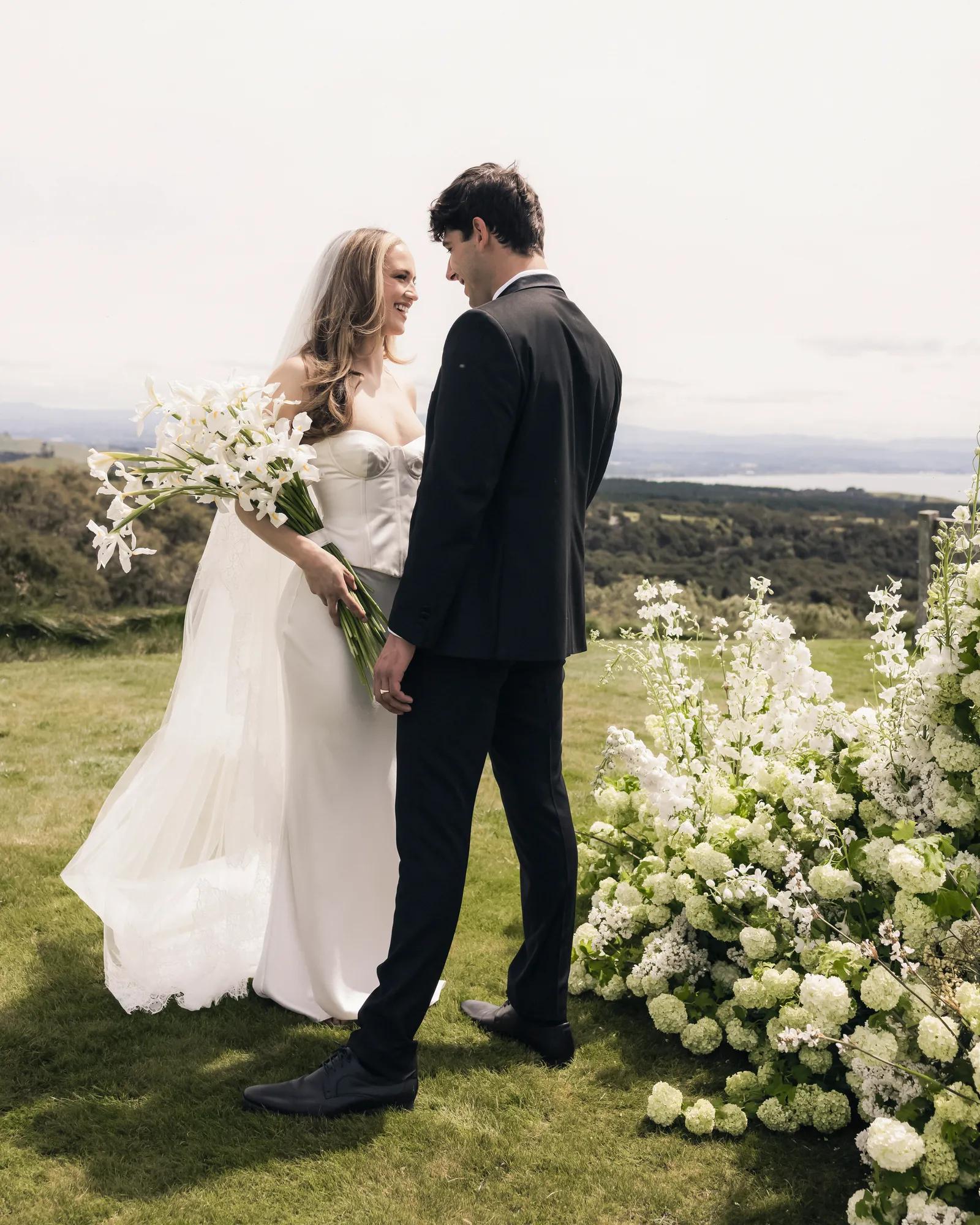Couple stand looking out the window of a luxury villa at Rosewood Cape Kidnappers with refined countryside interiors.