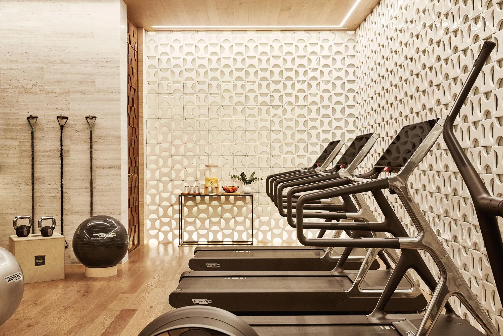 Fitness room equipped with a running machines, free weights, and an exercise ball, arranged in a clean and well-lit space