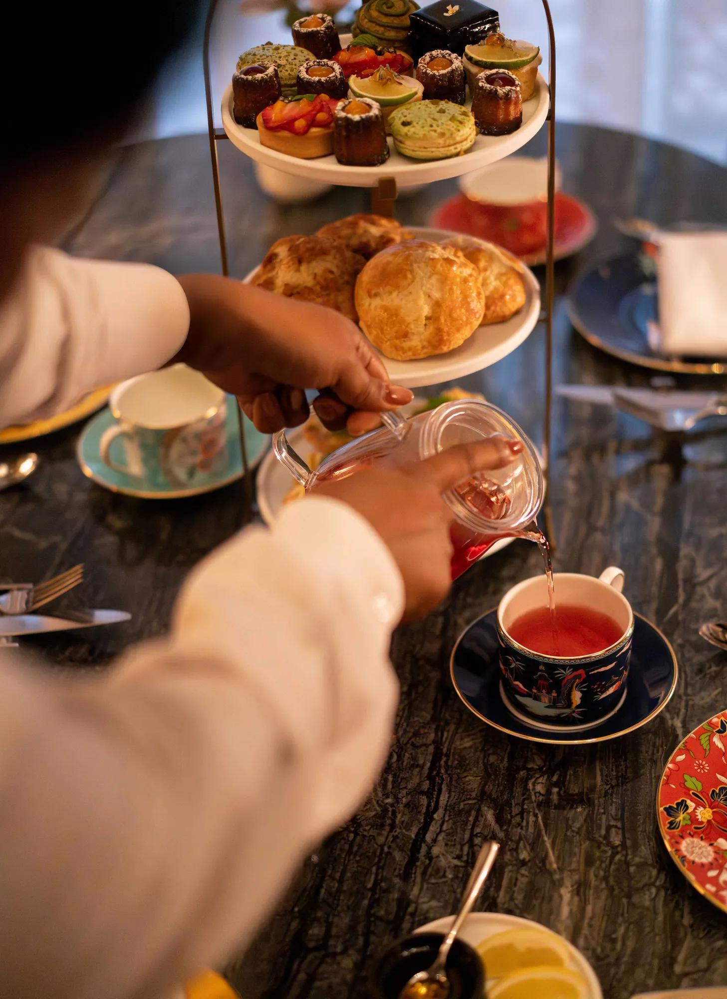 Tea pouring in elegant cup and pastries