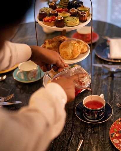 Tea pouring in elegant cup and pastries