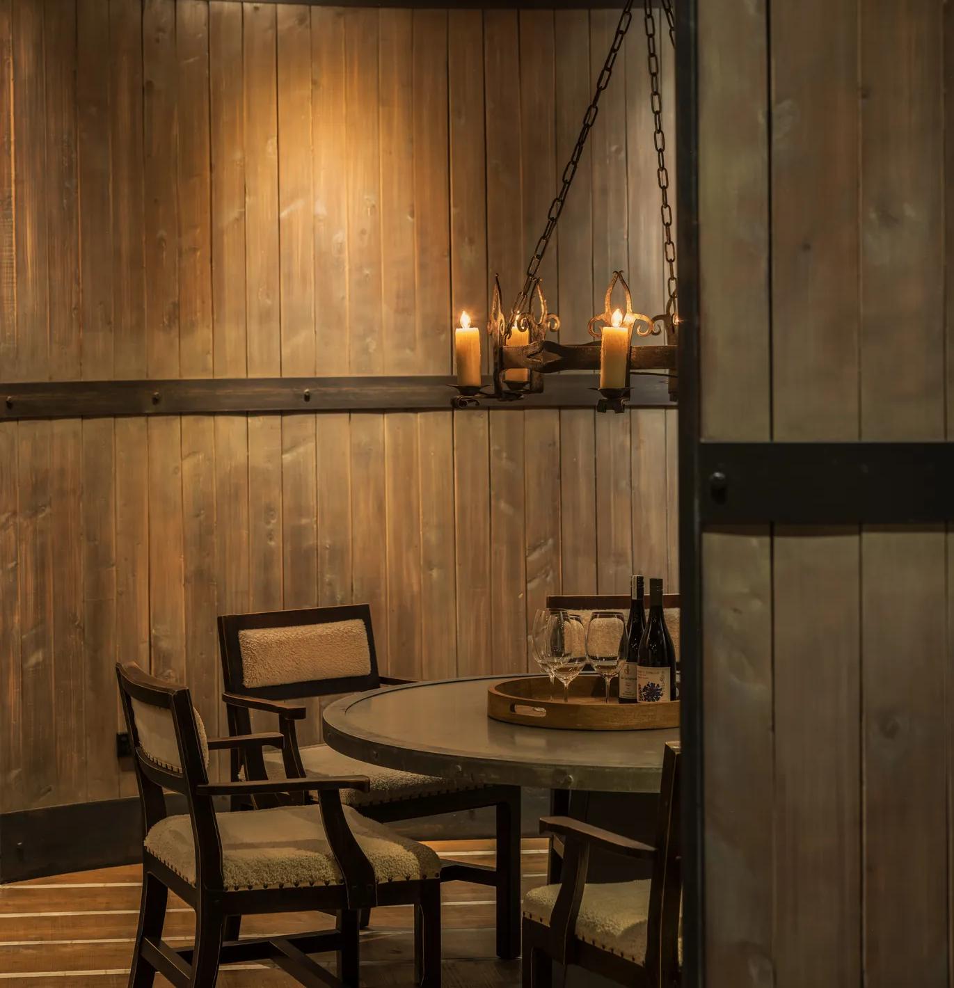 Private dining set up in round room with wood panelled walls and chandelier.