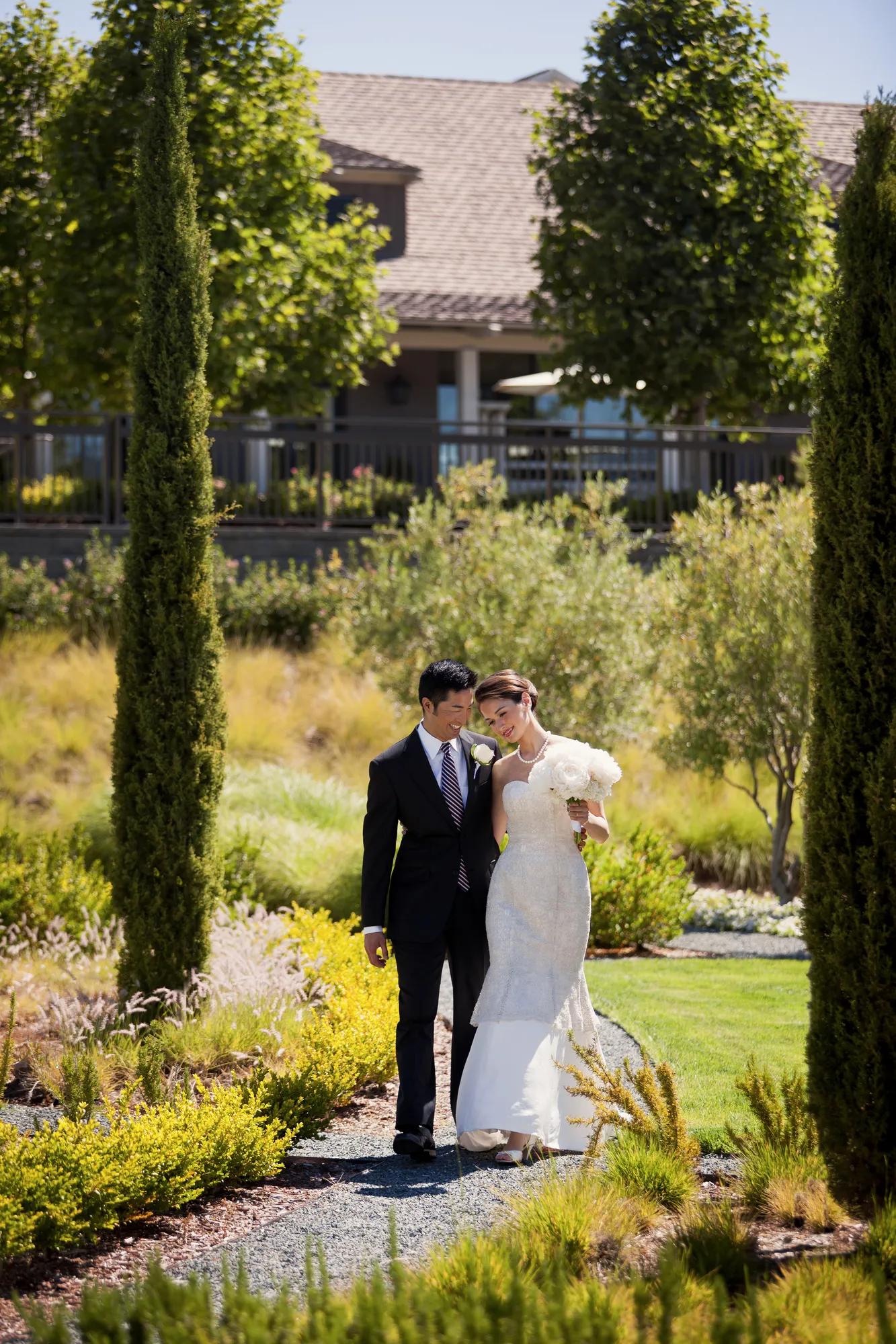 A bride and groom share a moment beneath the archways of Rosewood Sand Hill, with the gardens and Santa Cruz Mountain backdrop framing the beginning of forever.