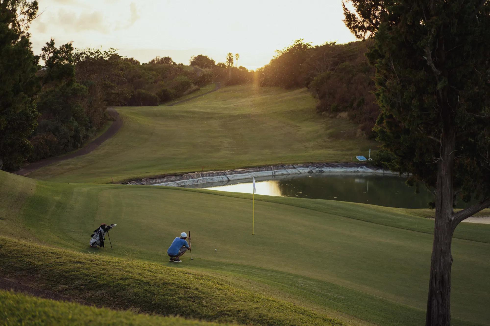 Man squatting while looking to make a shot at the hole