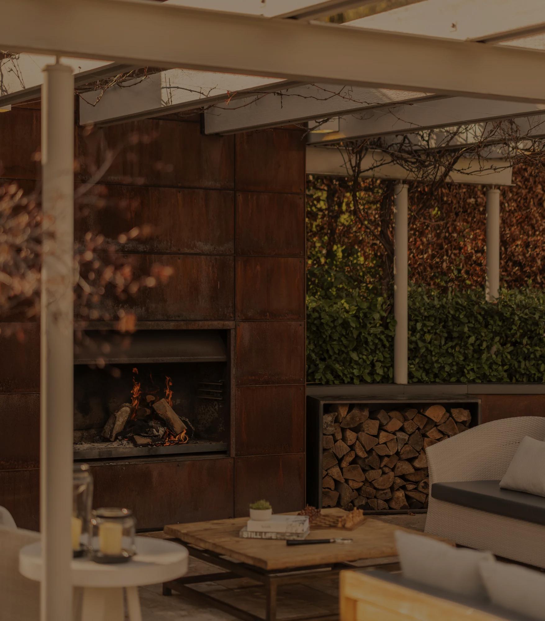 Fireplace in a luxury villa at Rosewood Matakauri with steel surrounds and mirror above that is reflecting the views of Lake Wakatipu and snowcapped mountains.