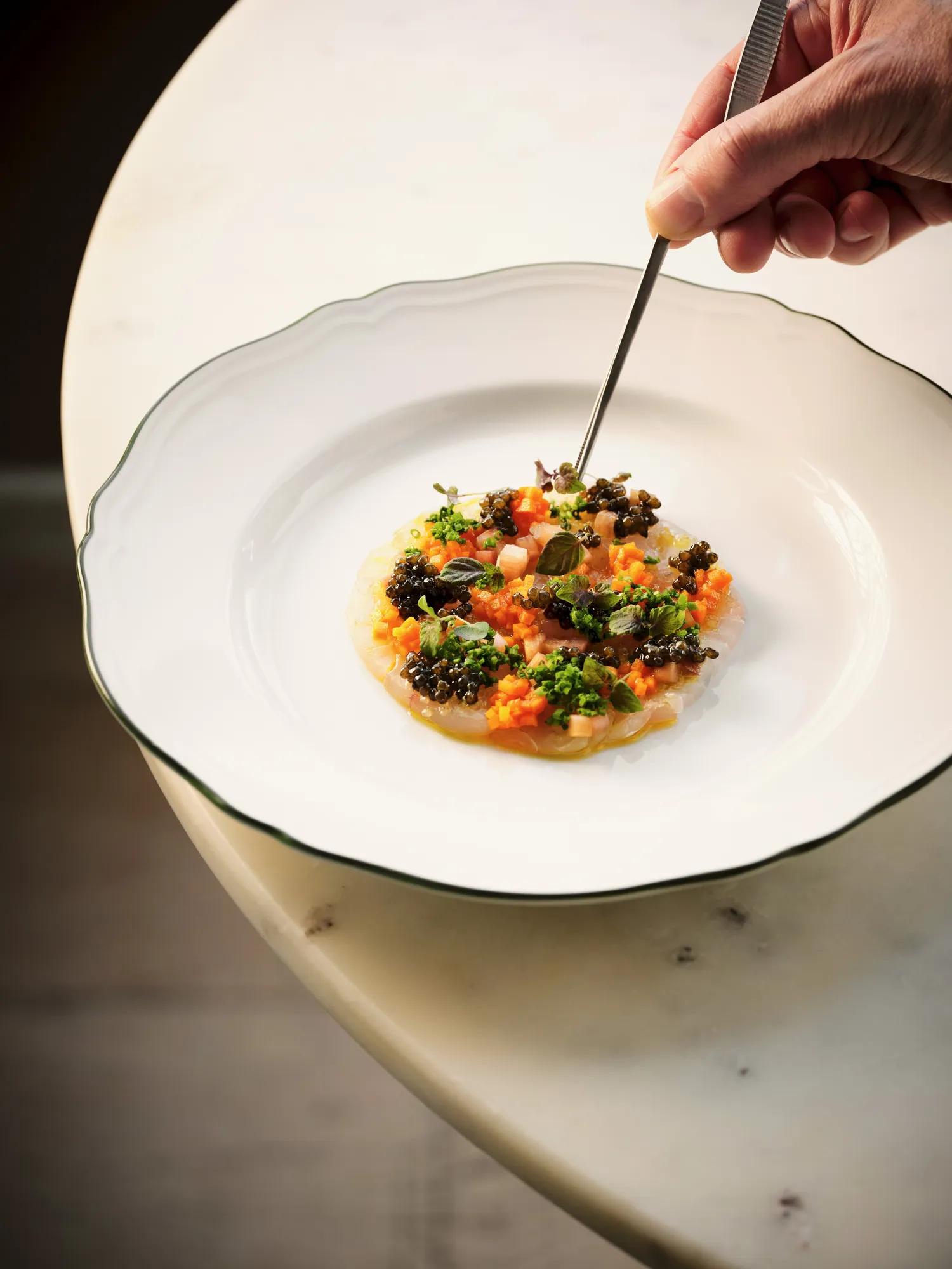 Beautifully plated salmon bruschetta served on a marble table accompanied by fresh sough dough and a glass of white wine. 