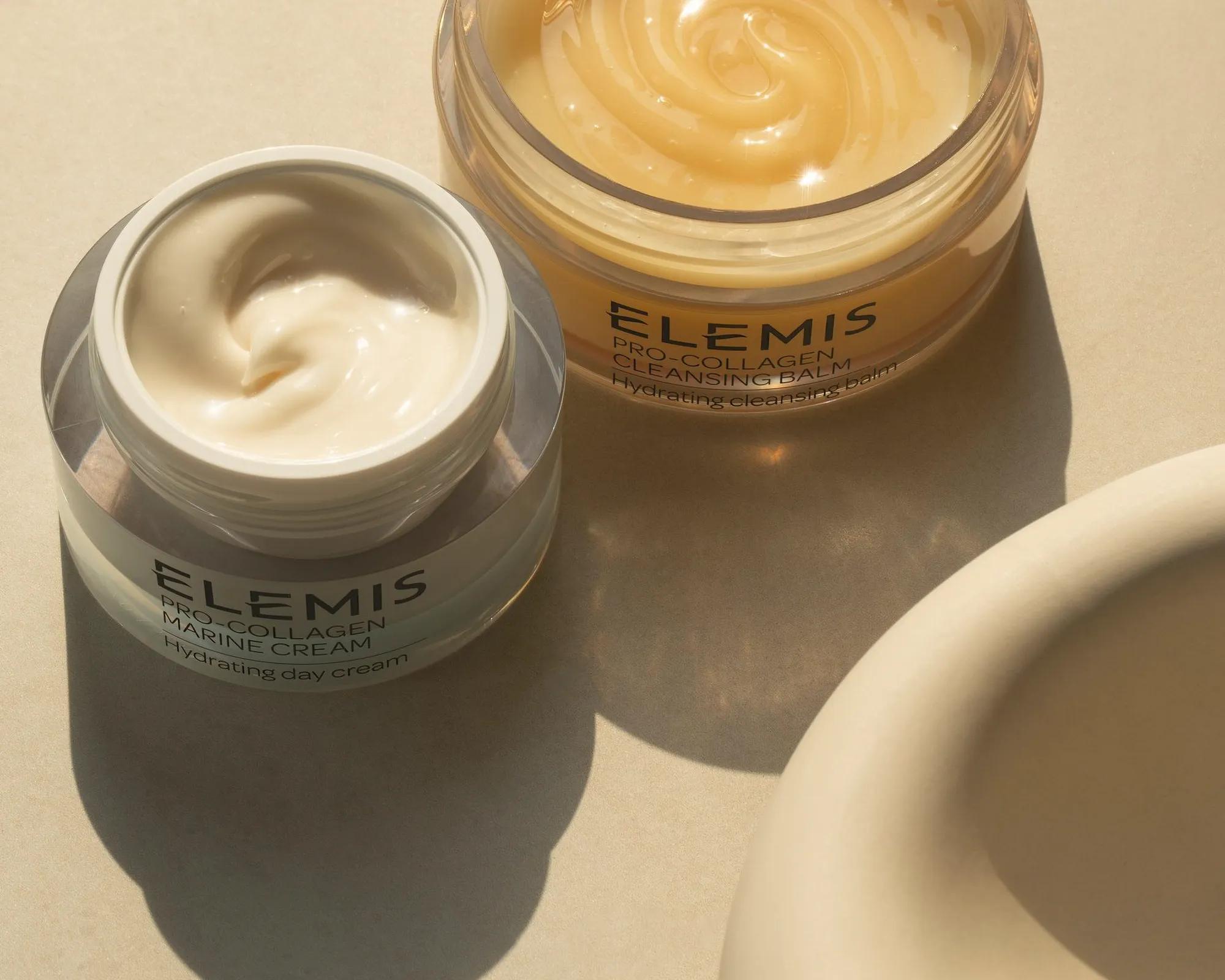 Woman laying on a spa bed with her eyes closed as she gets her temples massaged, in the background is a stack of three ELEMIS products.