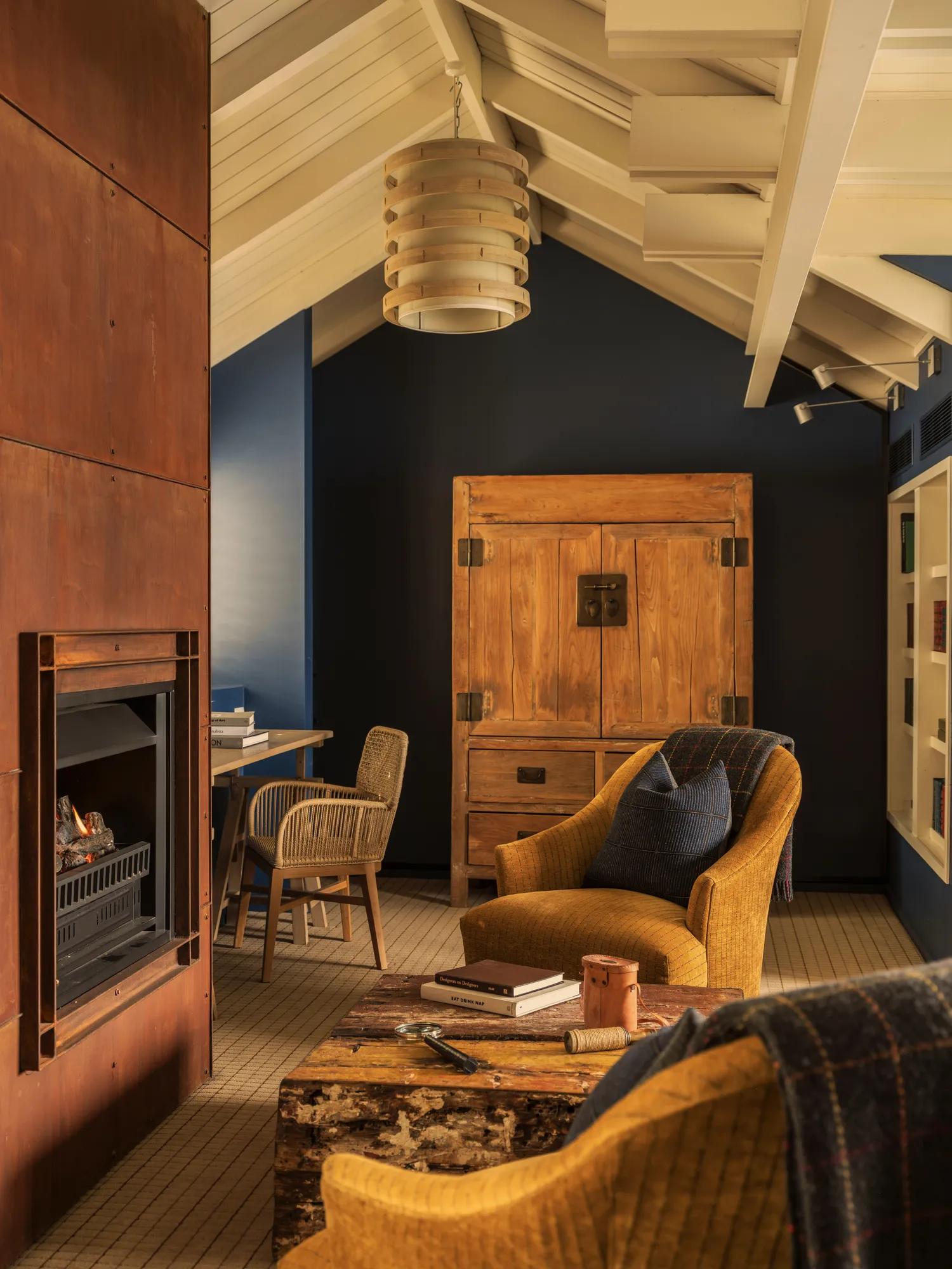 Cosy fireside setting next to a Corten steel fireplace in the Librabryt at Rosewood Matakauri. 