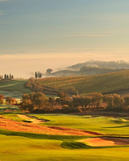 Aerial view of a golf course with tree-lined paths, rolling hills, and sand bunkers.