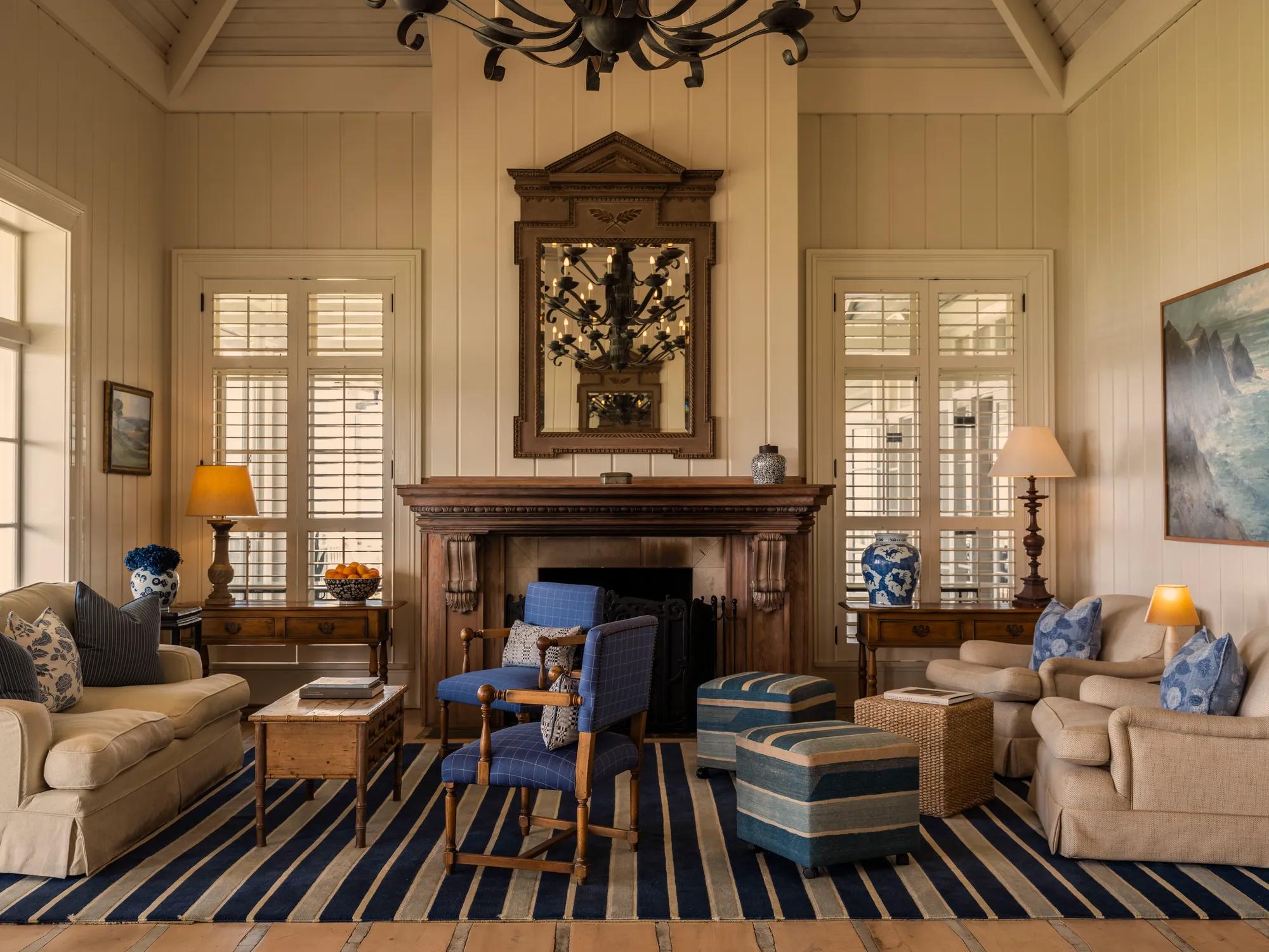 Main lounge at Rosewood Kauri Cliffs with elevated interiors including comfortable seating, a grad chandelier and a selection of artworks and artifacts. 