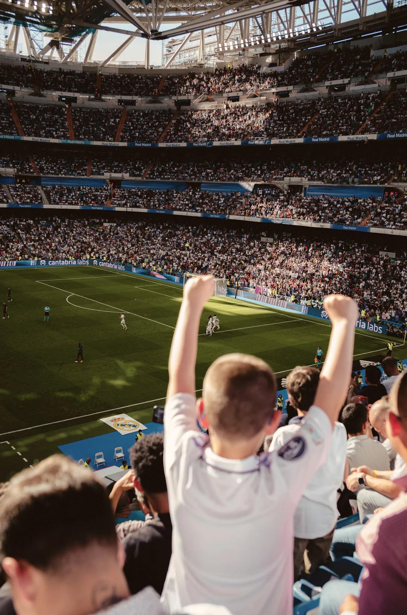 child cheering during a football match at Santiago Bernabéu Stadium