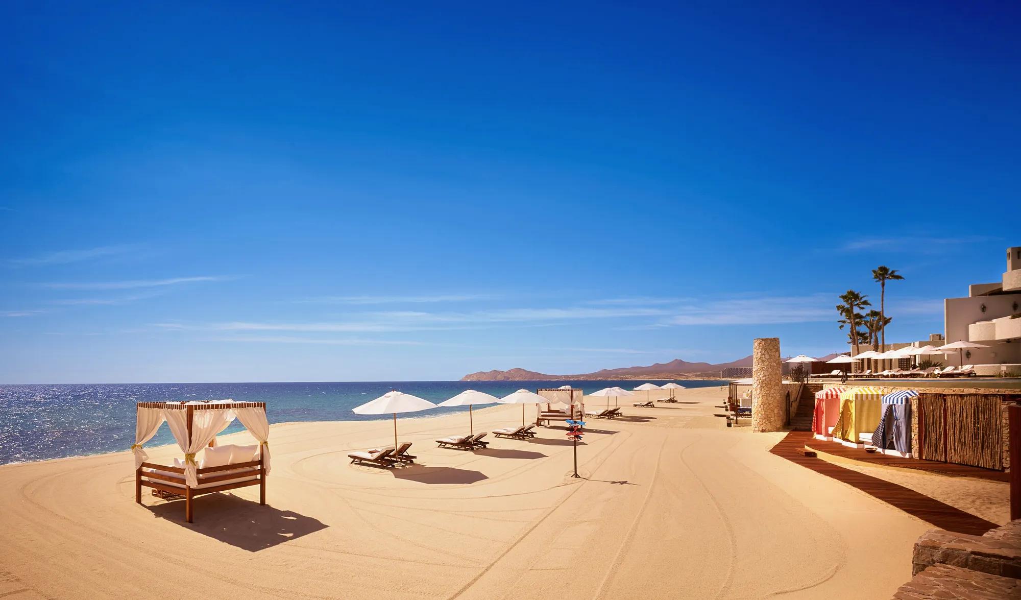 Pristine Los Cabos beach with clean white sand and oversized luxury beach beds.