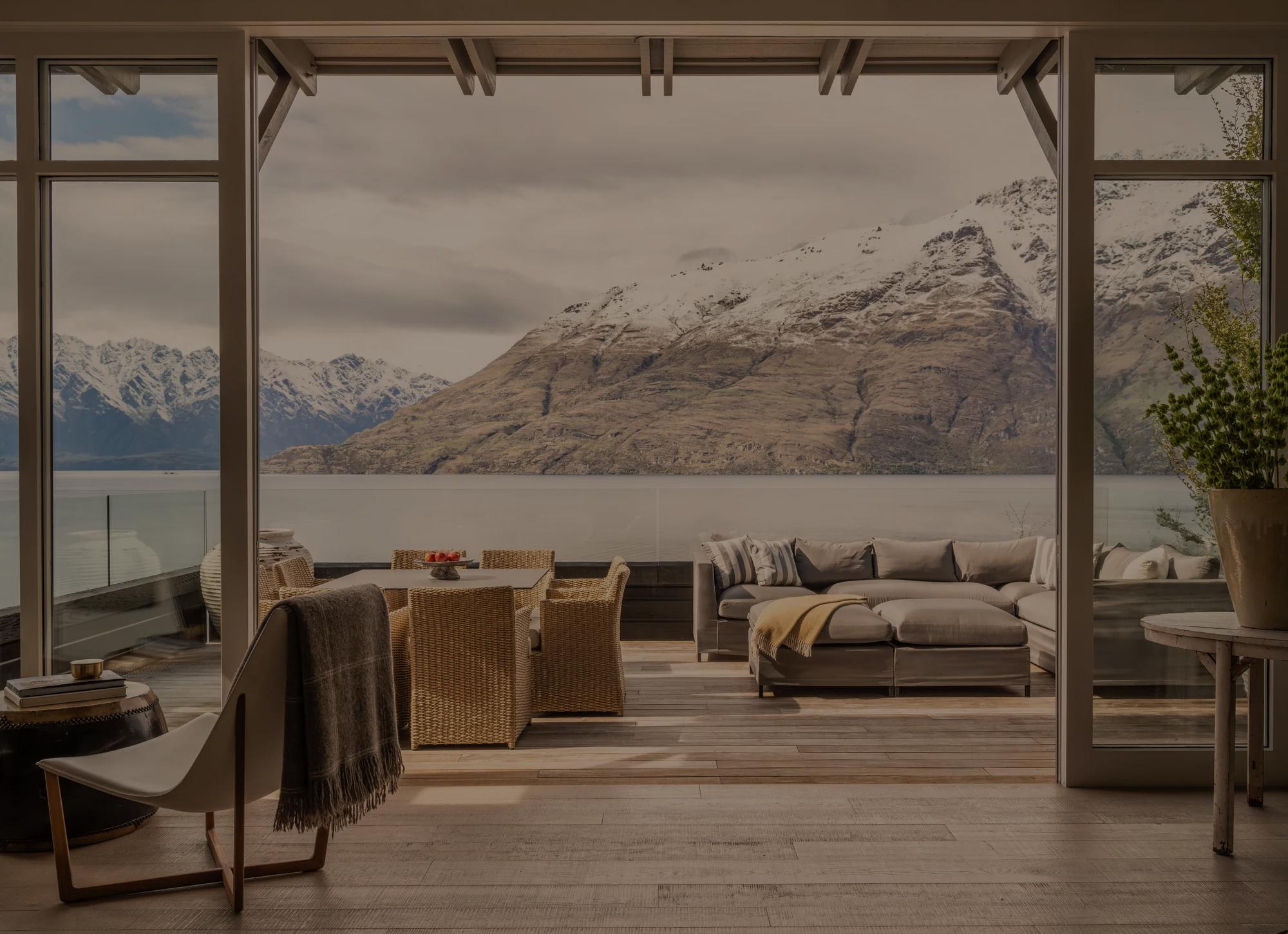 View of a spacious balcony in a luxury villa at Rosewood Matakauri looking out to Lake Wakatipu and the surrounding snowcapped mountains. 