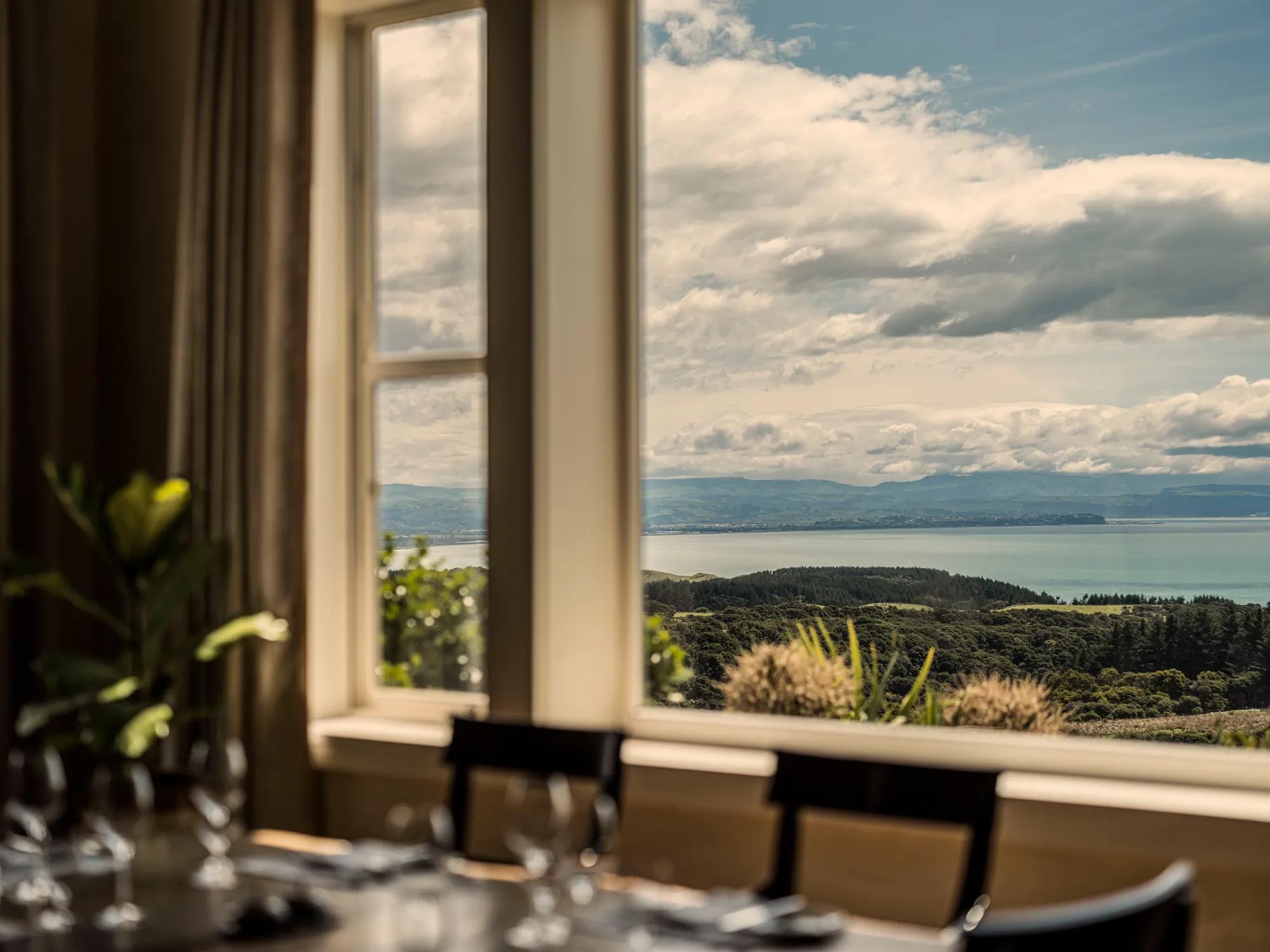 Countryside and ocean view from a dining room window in a luxury lodge