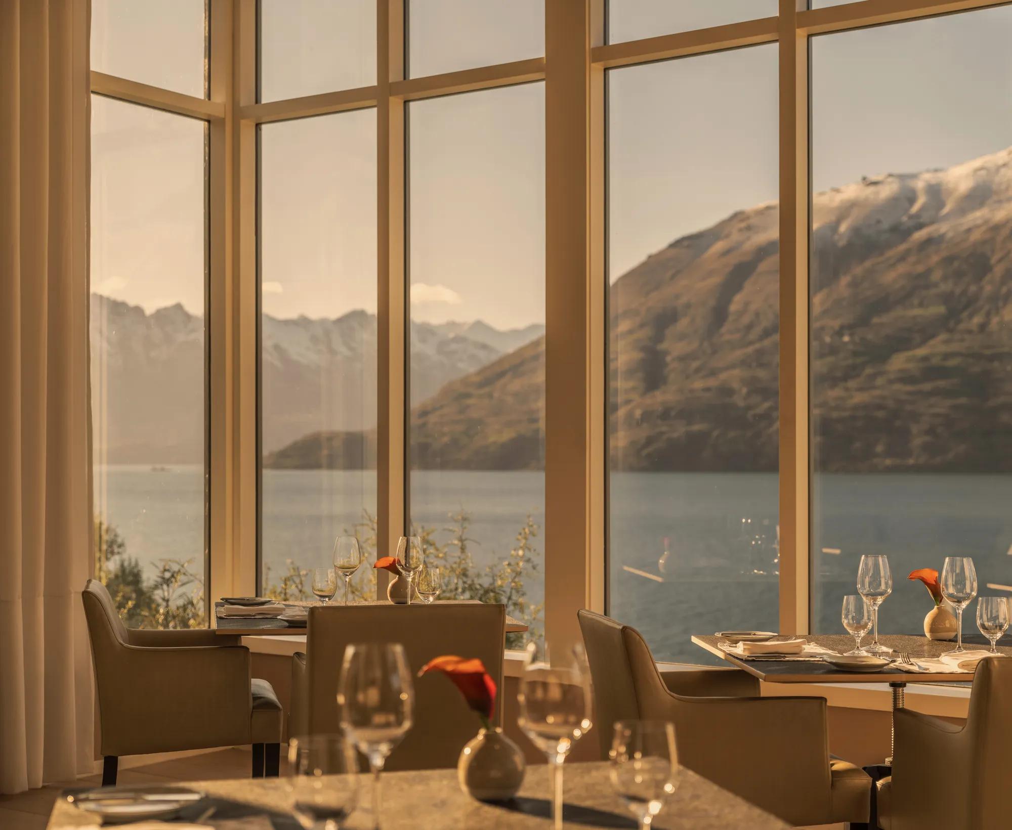 Beautifully set tables in The Dining Room at Rosewood Matakauri with big picture windows to the lake and mountain views.