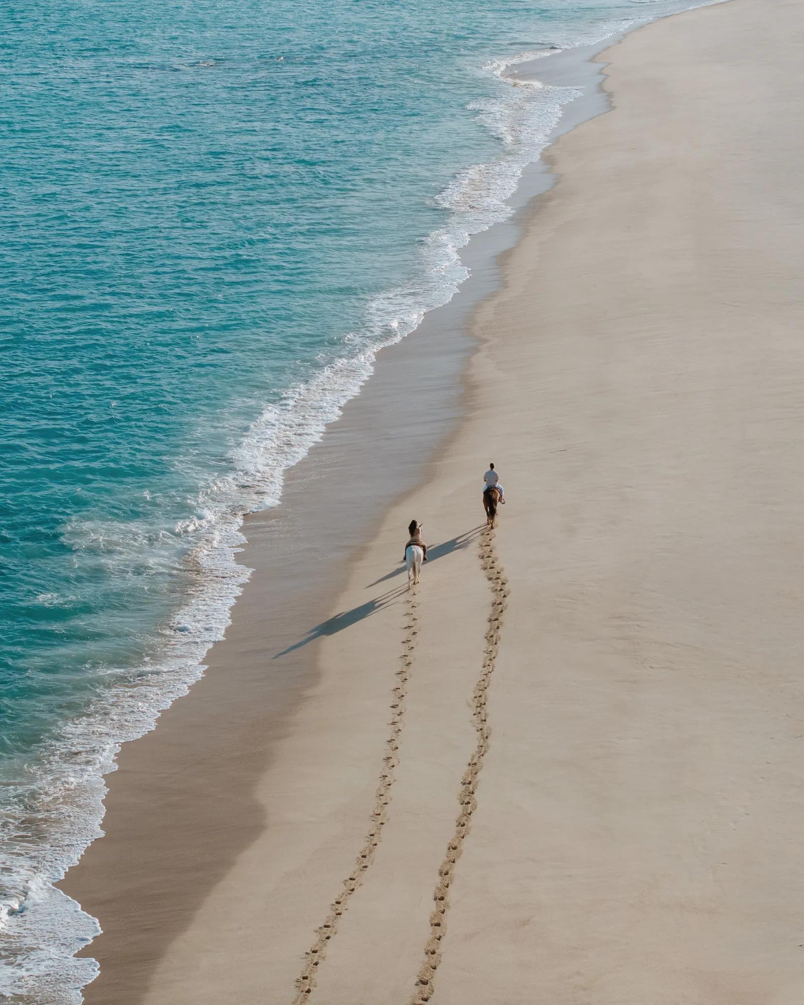 Couple horseback riding on beach
